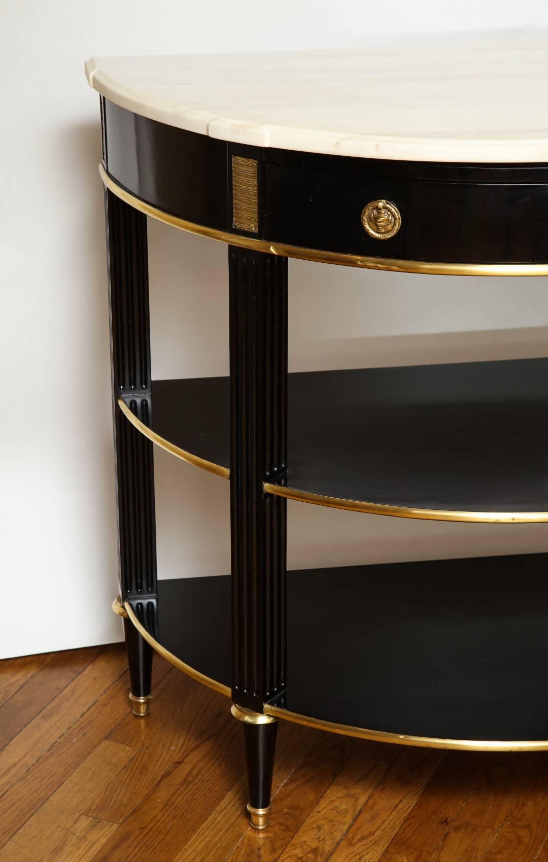 A French ebonized brass mounted console dessert, the new white marble top resting on a frieze with a faux drawer and ring handles, the reeded legs with brass collars terminating in toupie feet, newly ebonized walnut carcass with French polish finish