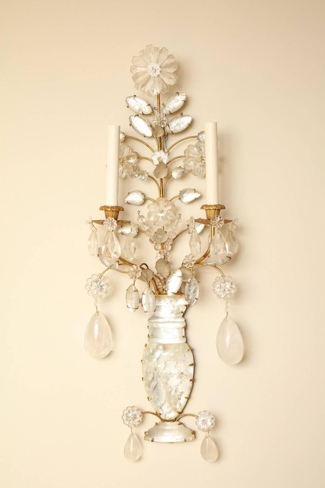 A pair of new rock crystal two-light wall sconces with gilt-metal frames, the backplate in the form of a vase issuing two candle arms and branches with crystal leaves, the candle arms draped with rock crystal drops 
