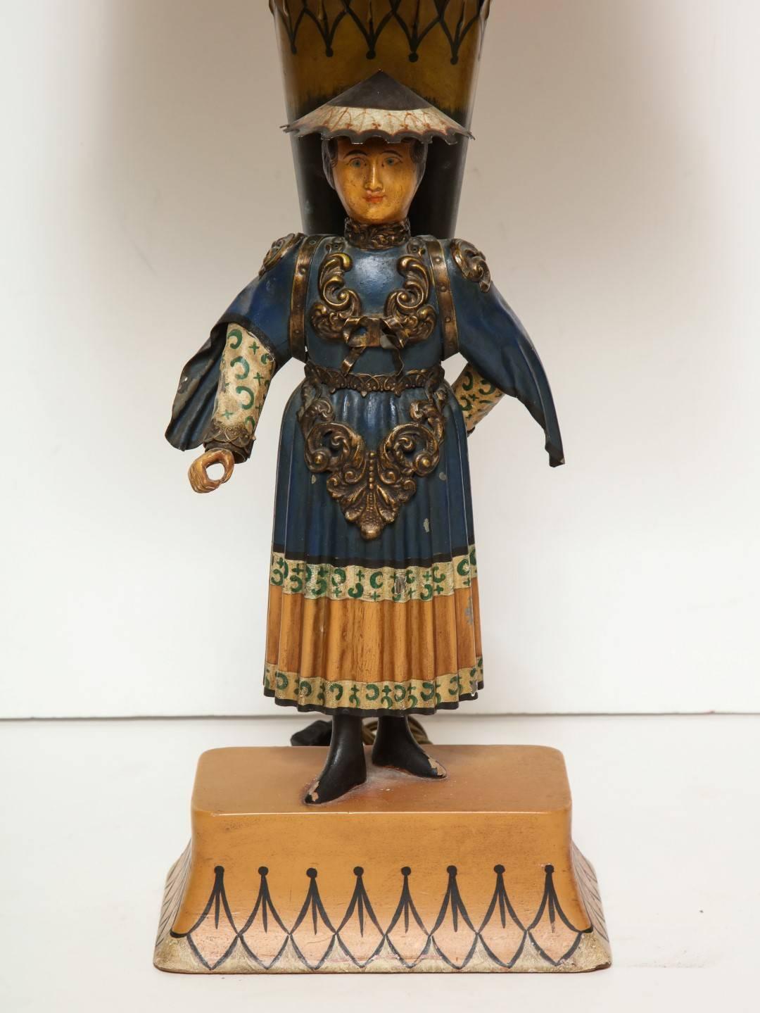 A French tole peinte Chinese female figure in Asian inspired costume holding basket; details with polychrome decoration on custom rectangular base fitted as lamp.