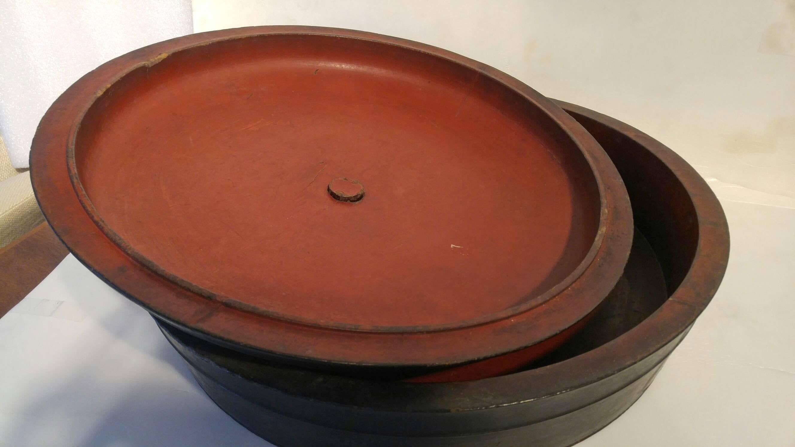 A black teak wood round bowl with cover from South Borneo. Red interior, 19th century.