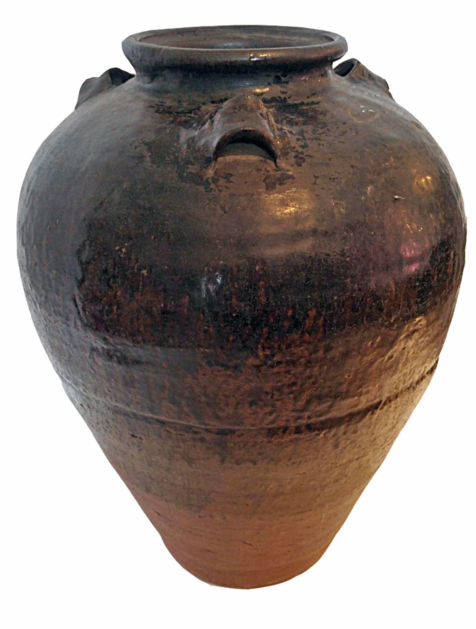 A large clay pot, vase or urn with ears and a dark glaze, from India.