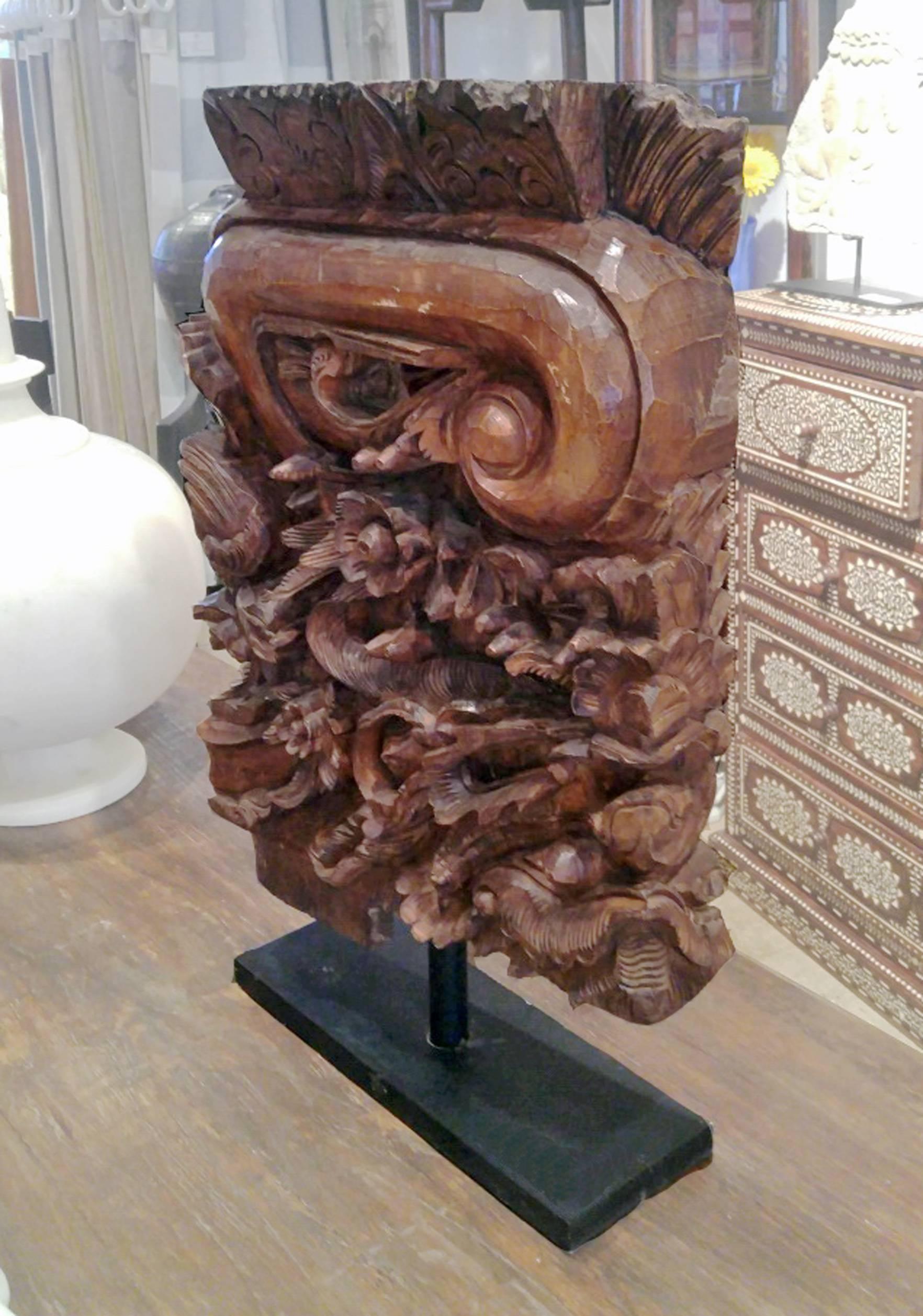 A hand-carved architectural detail in teak wood, from  Mounted on a metal stand. A dramatic, yet sophisticated accent for an eclectic decor. 
