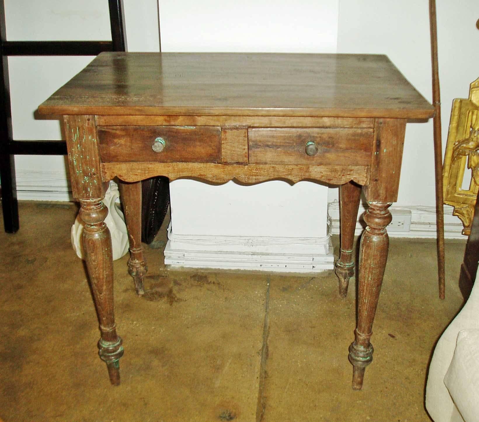 A small side table or console with two drawers, turned legs and scalloped apron, from Indonesia.