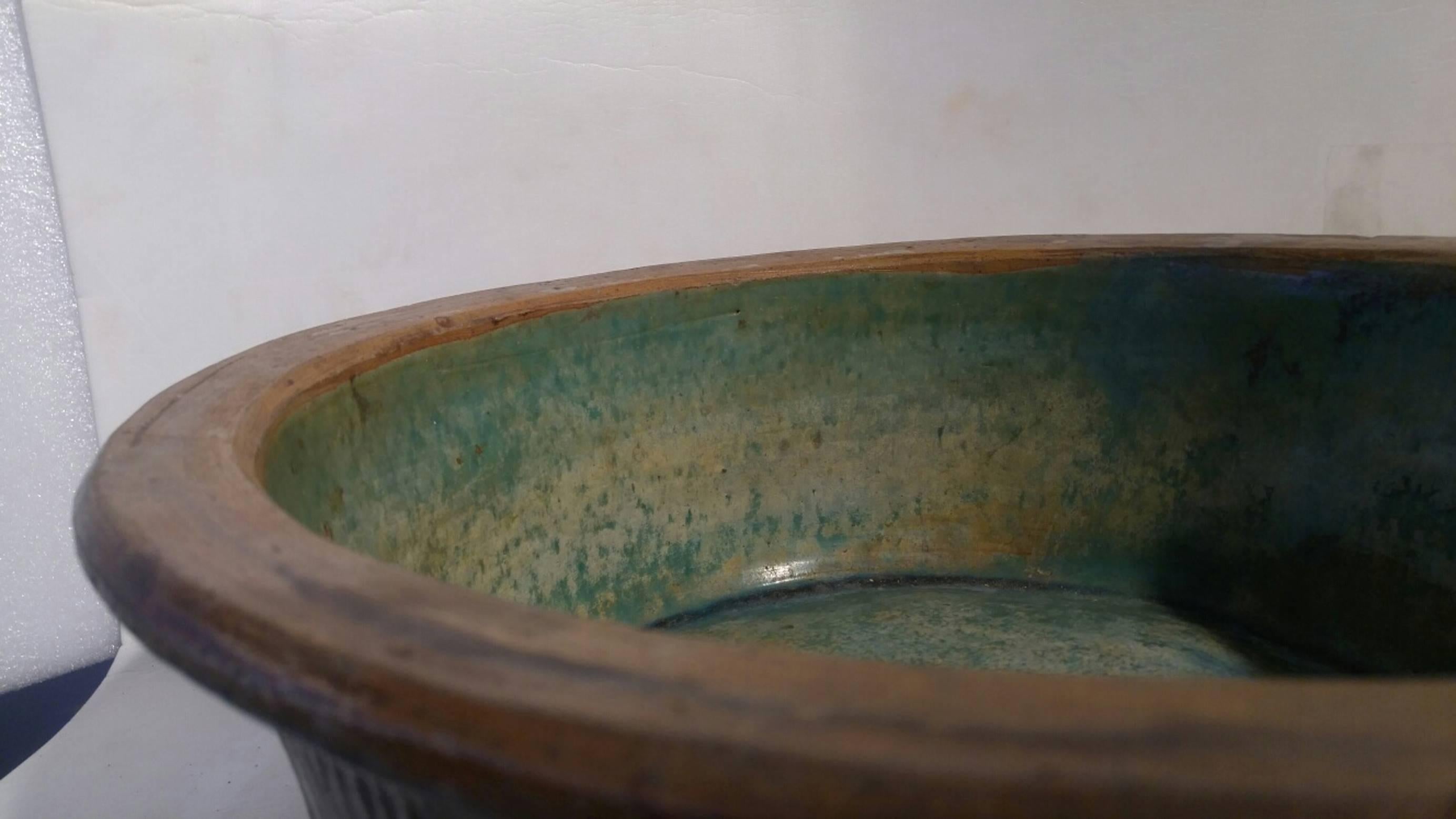 A tall and large ceramic bowl from Indonesia with brown ridged exterior and a green glazed interior.