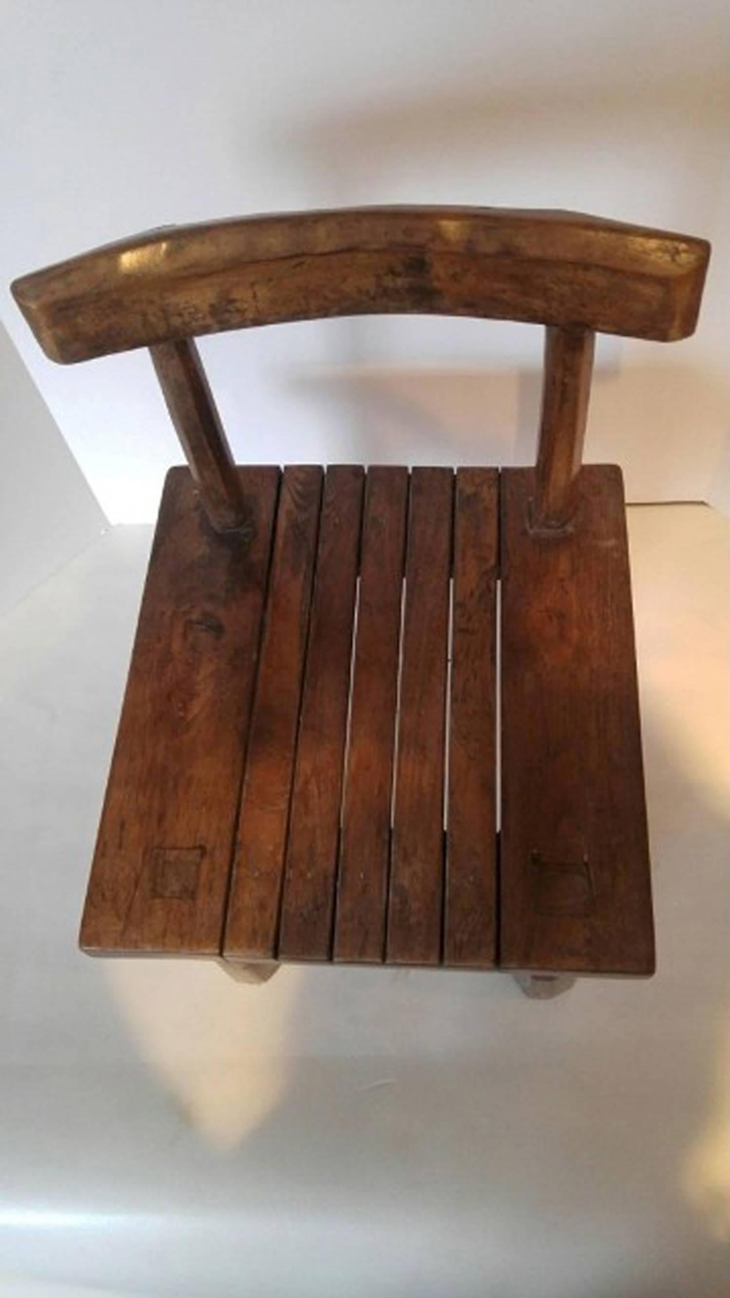 A small carved teak chair with slatted seat. Use as a low table or stand.