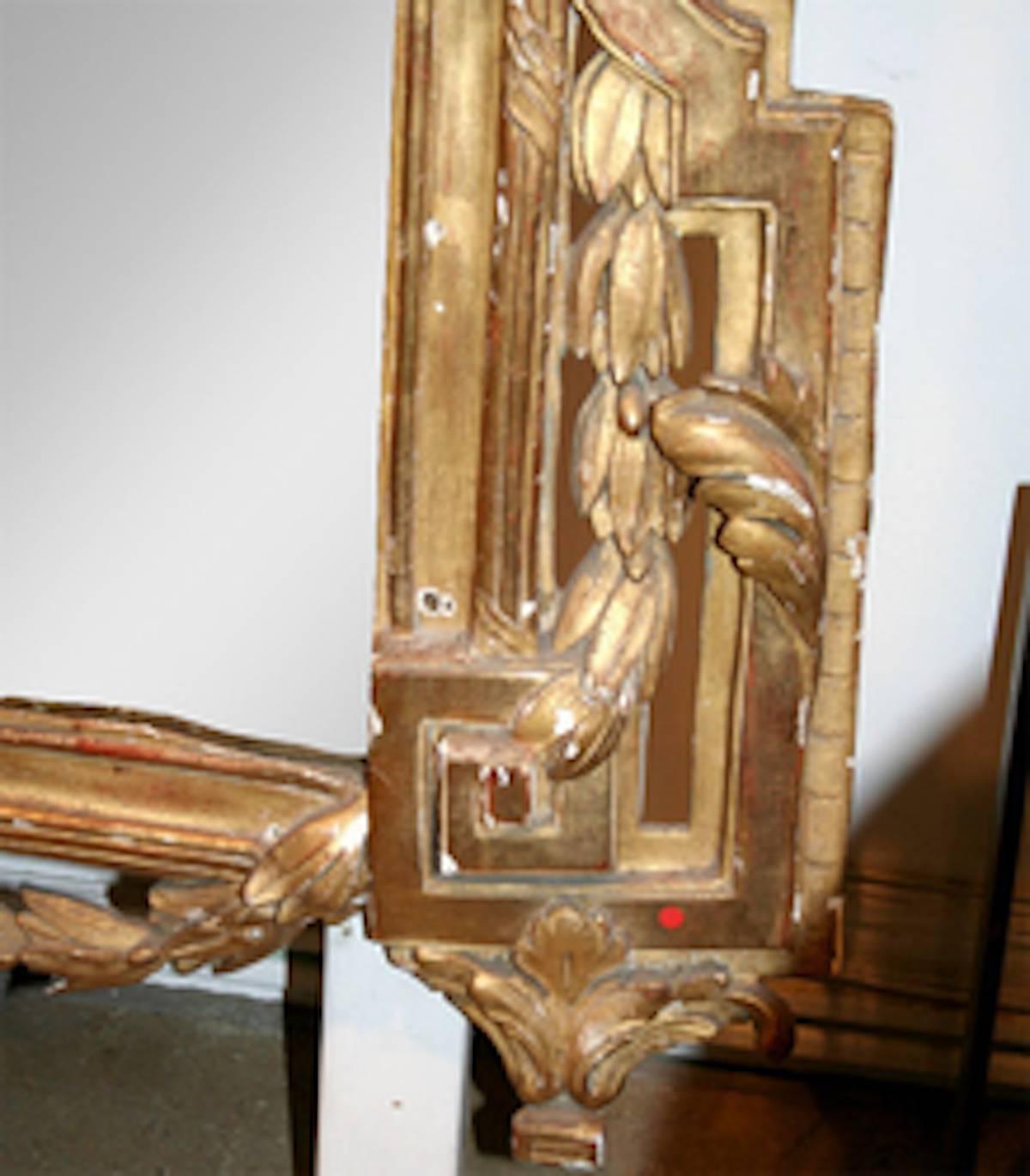 An 18th century Louis XVI wall or mantel mirror with original glass and a frame of wood, gesso and gilt, with grand floral reliefs. Some restoration of gilt and gesso may be desirable. Requires professional shipping and installation.