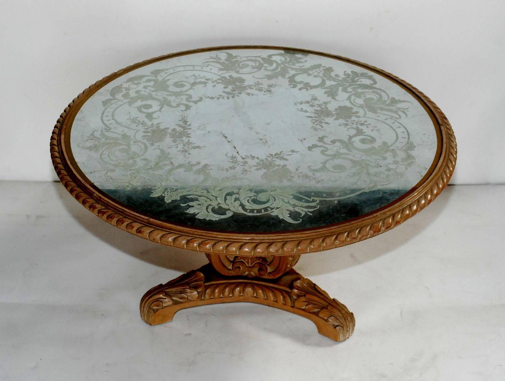 Elegant hand-carved wood coffee table Grosfeld House New York. Neoclassic style reverse painted silver leaf églomisé glass top.