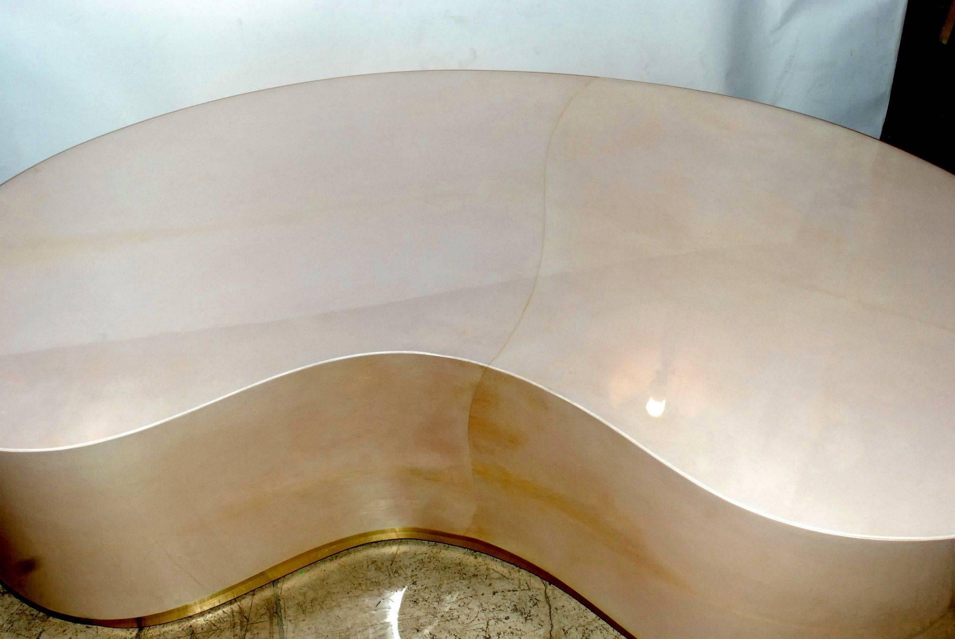 Mid-Century Modern style coffee table is covered in goatskin and brass kick base. Parchment is in varying shades of natural finish. (High gloss polyester resin filled finish).