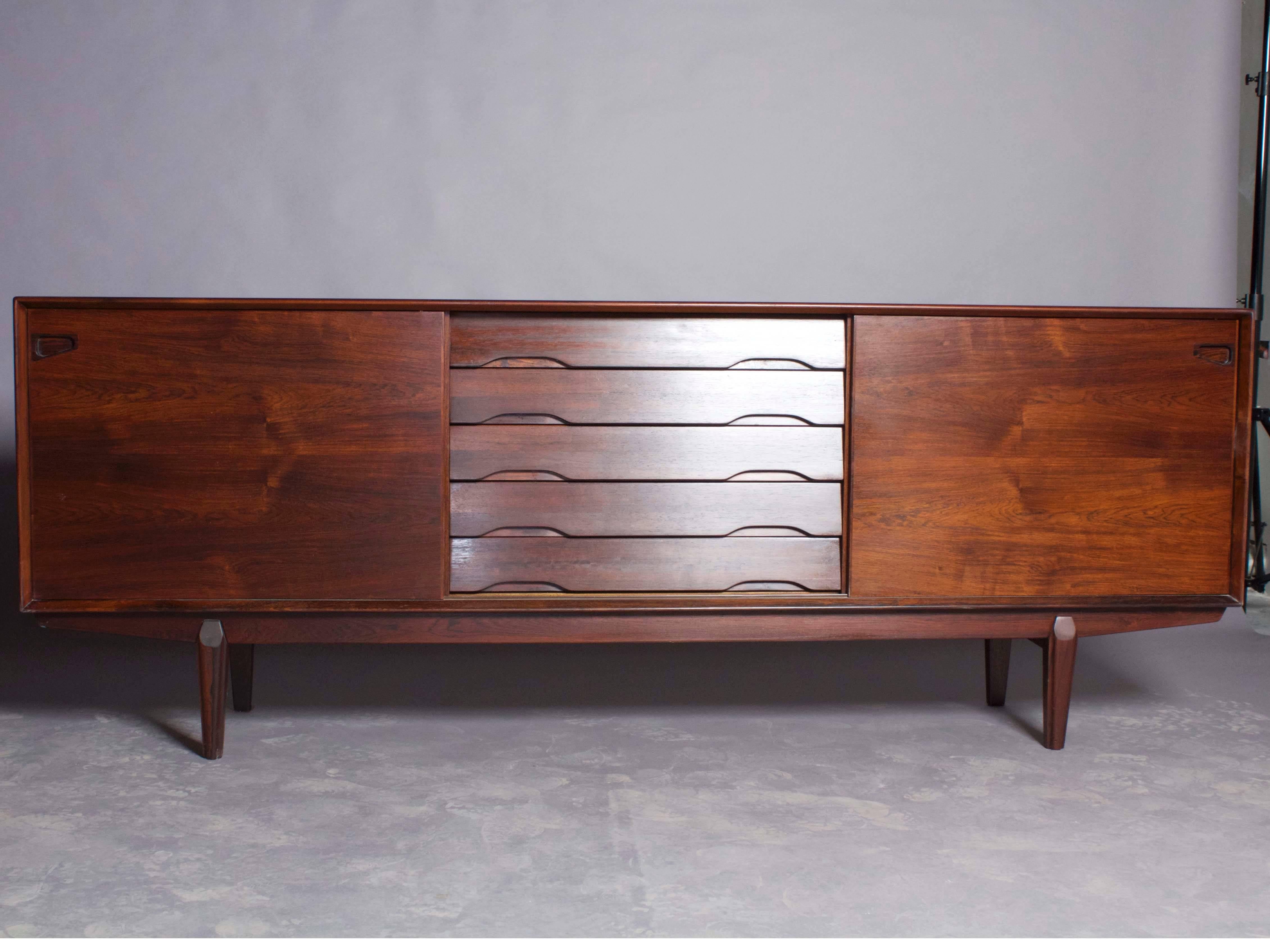 Vintage 1960s Danish credenza in rosewood.

This vintage cabinet is amazing in it's very simple form. This cabinet has the most basic and useful with it's adjustable shelving on either side that is accessible sliding door, and it's middle section