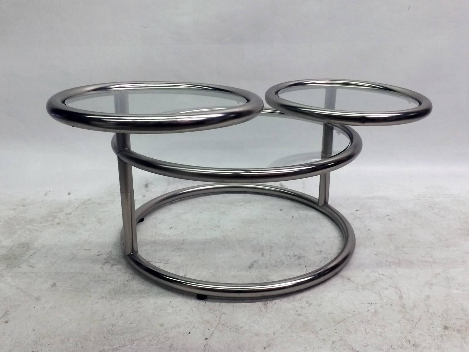 This coffee table features three tubular chrome and glass surfaces. The two top ones both swivel independently allowing the table to expand in size.