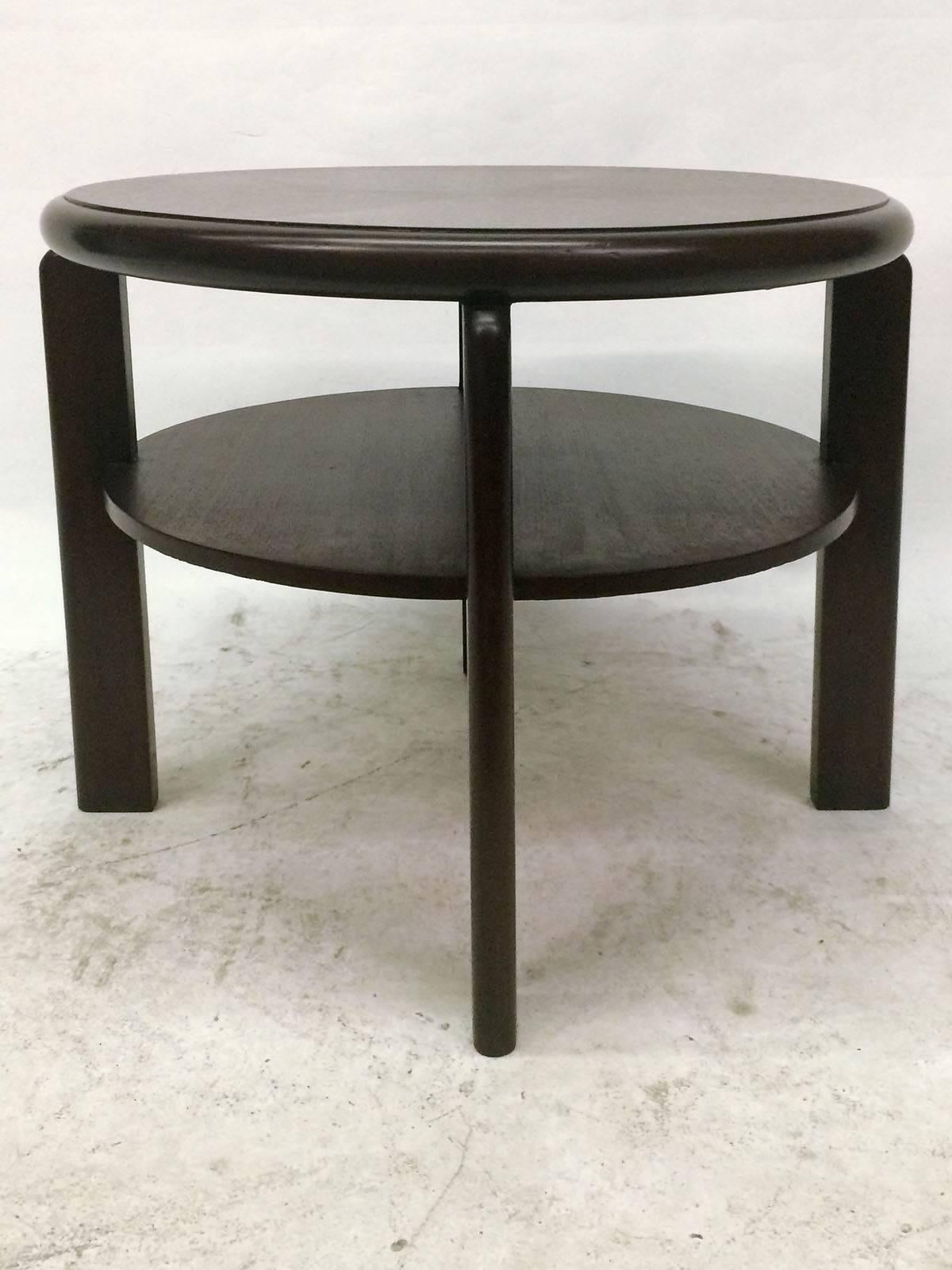 Round four-legged Art Deco table in dark stained mahogany, soft edges. The table's top is constructed using a symmetrical starburst wood inlay pattern and also has a lower round shelf.