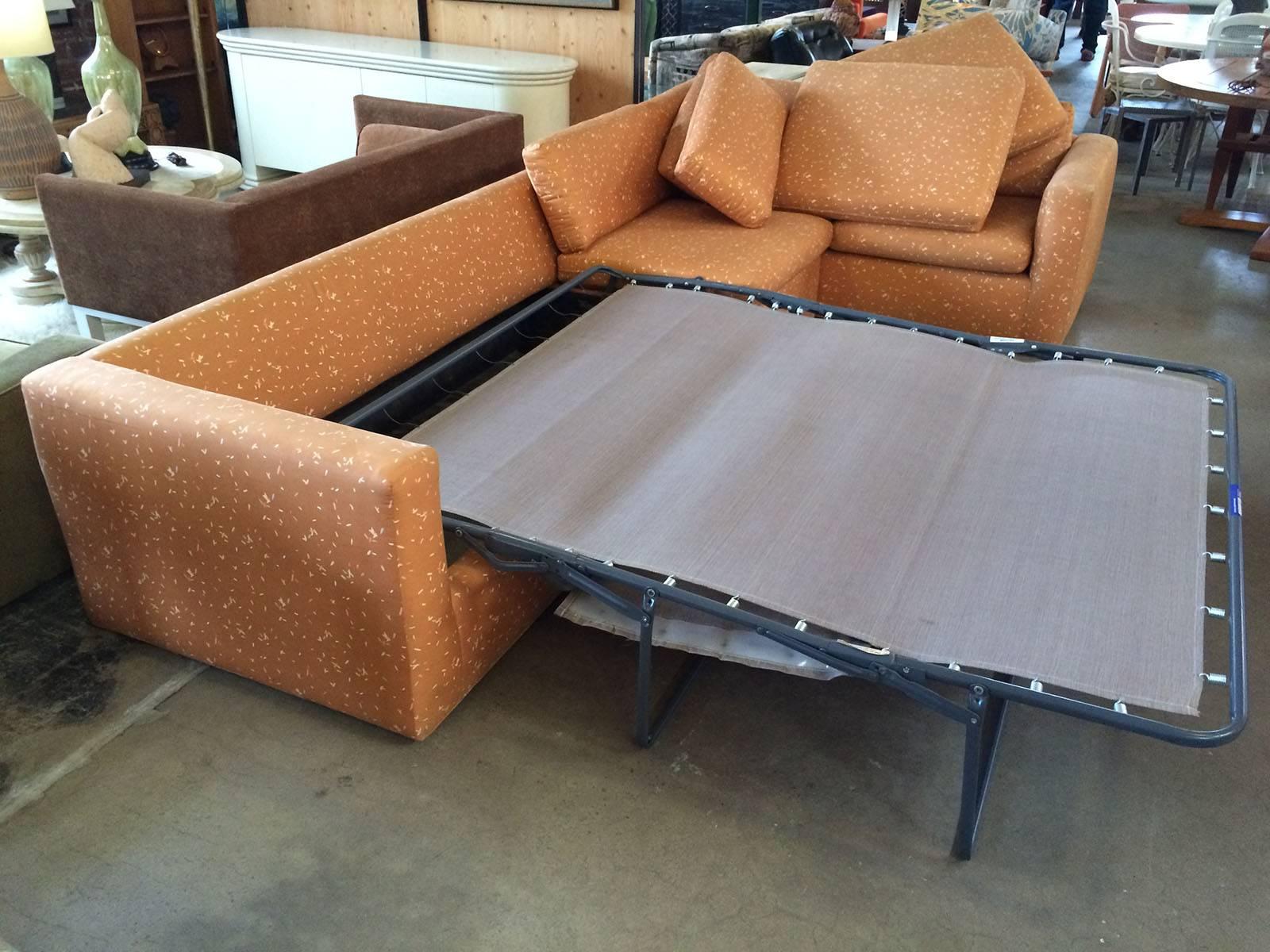 Large sectional sofa with pullout bed by Rothstein. Sofa is upholstered in playful orange/rust colored fabric. The pullout bed measures 63 wide X 37 long X 17 high, the small sofa section is 70 wide X 36 deep X 25 high X 17 seat height and the large