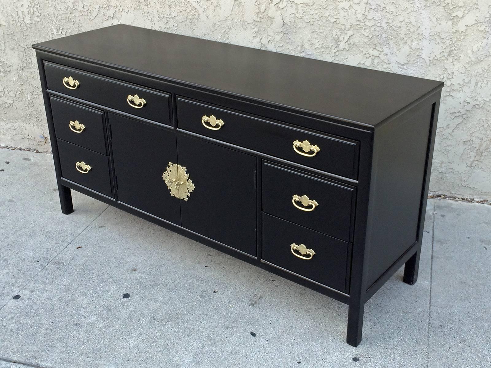 A buffet finished in black lacquer and finished with ornate brass handles. The buffet has six drawers and two doors that open to an adjustable shelf. The buffet was made by Willet and has original manufacture stamp.
Willett Furniture company was