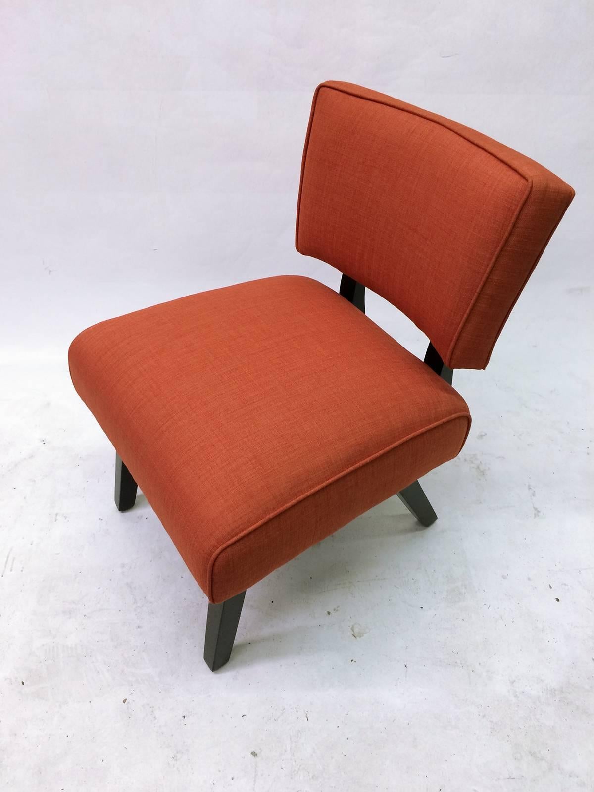 This is a Mid-Century slipper chair of solid ebonized wood construction and rust fabric upholstery. The chair has two springs under the seating surface that allow for a slight rocking tilting motion.