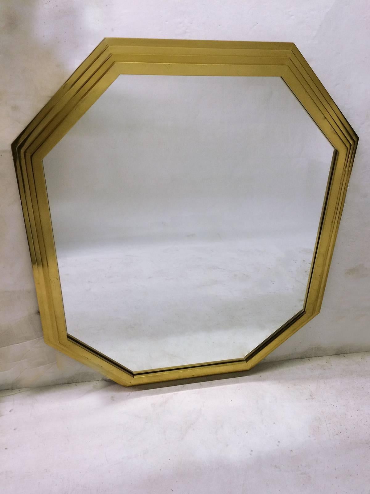 This octagonally-shaped mirror is framed in a stepped brass frame with four levels. Reflections and shadows on stepped frame create a very modern architectural feel. Mirror has sticker stating 