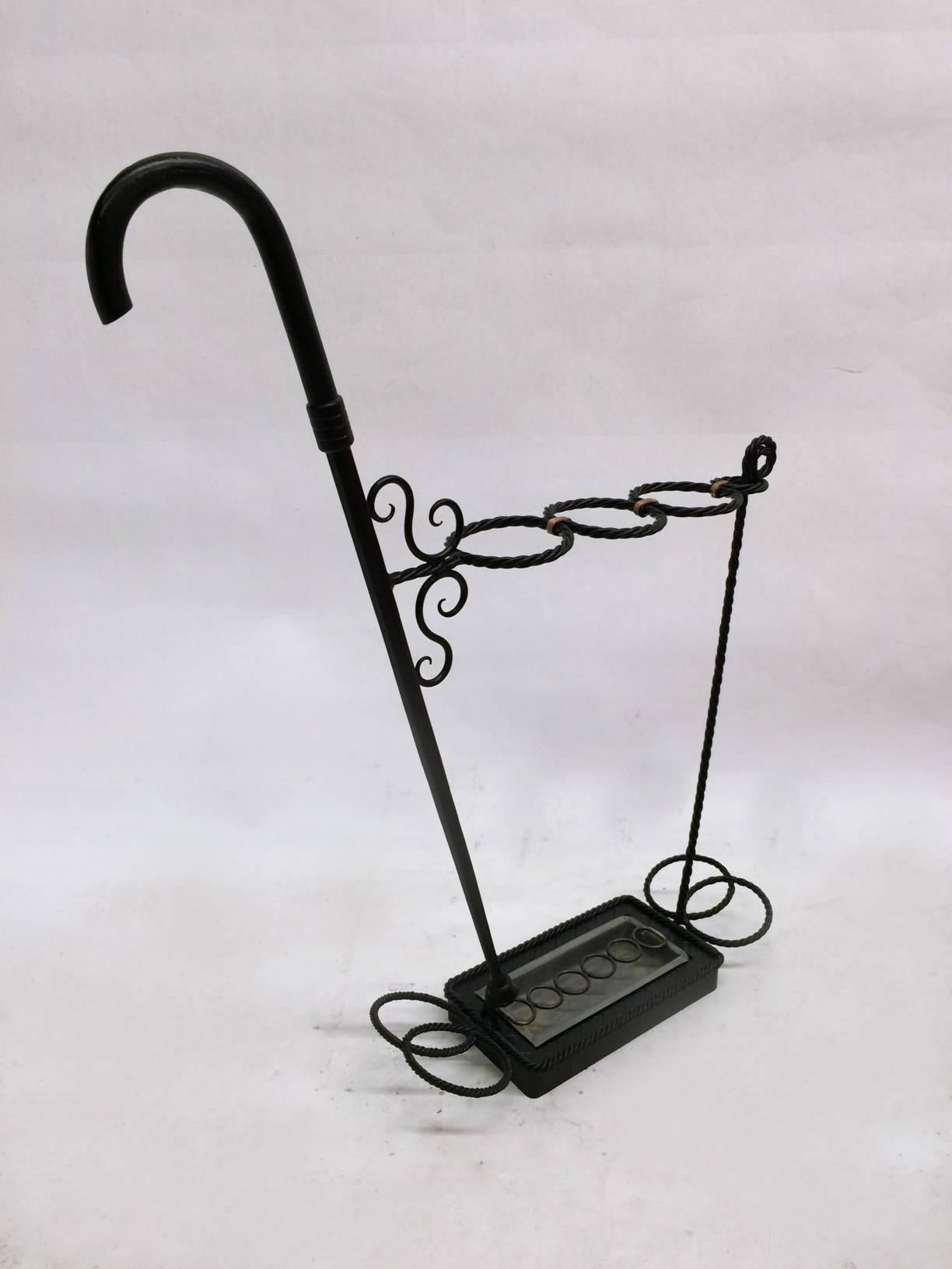 This umbrella stand is constructed of wrought iron steel and finished with copper embellishments. The steel is composed of thin strands woven like rope held together by copper rings and holding a removable tin base to collect water.