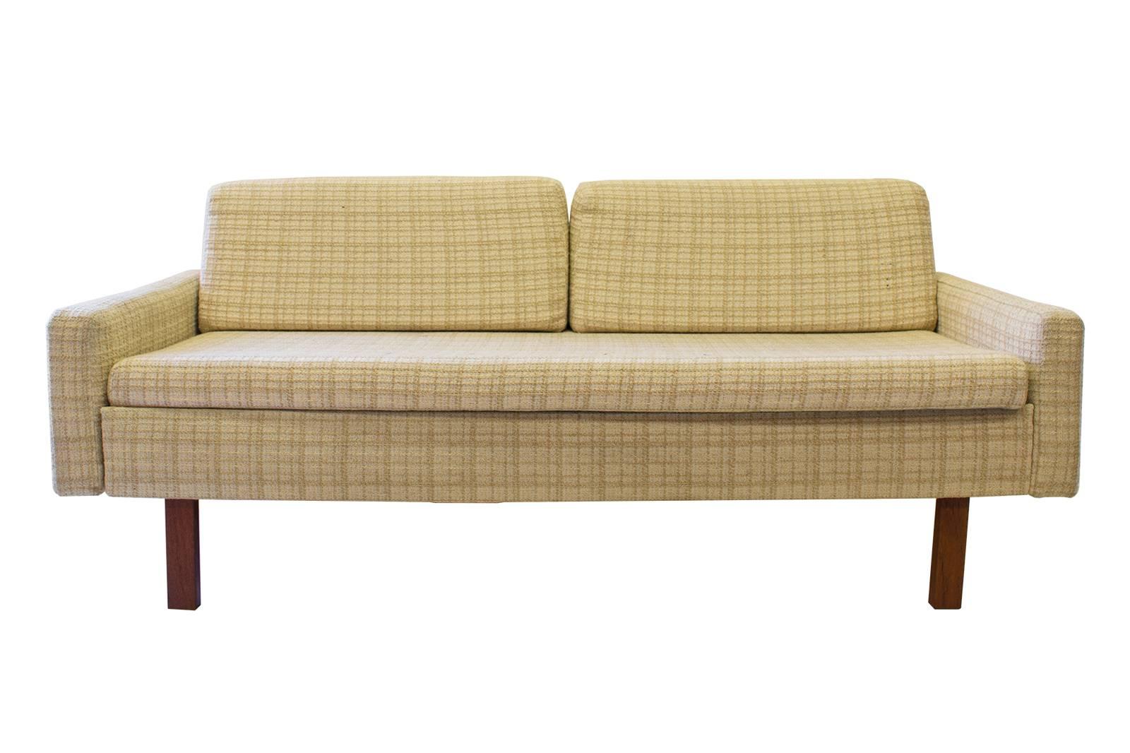 This small Mid-Century sofa has an hidden pull-out side table in teak. The piece has one large seat cushion and two wedge-shaped back cushions.
The side table open the width is 78".