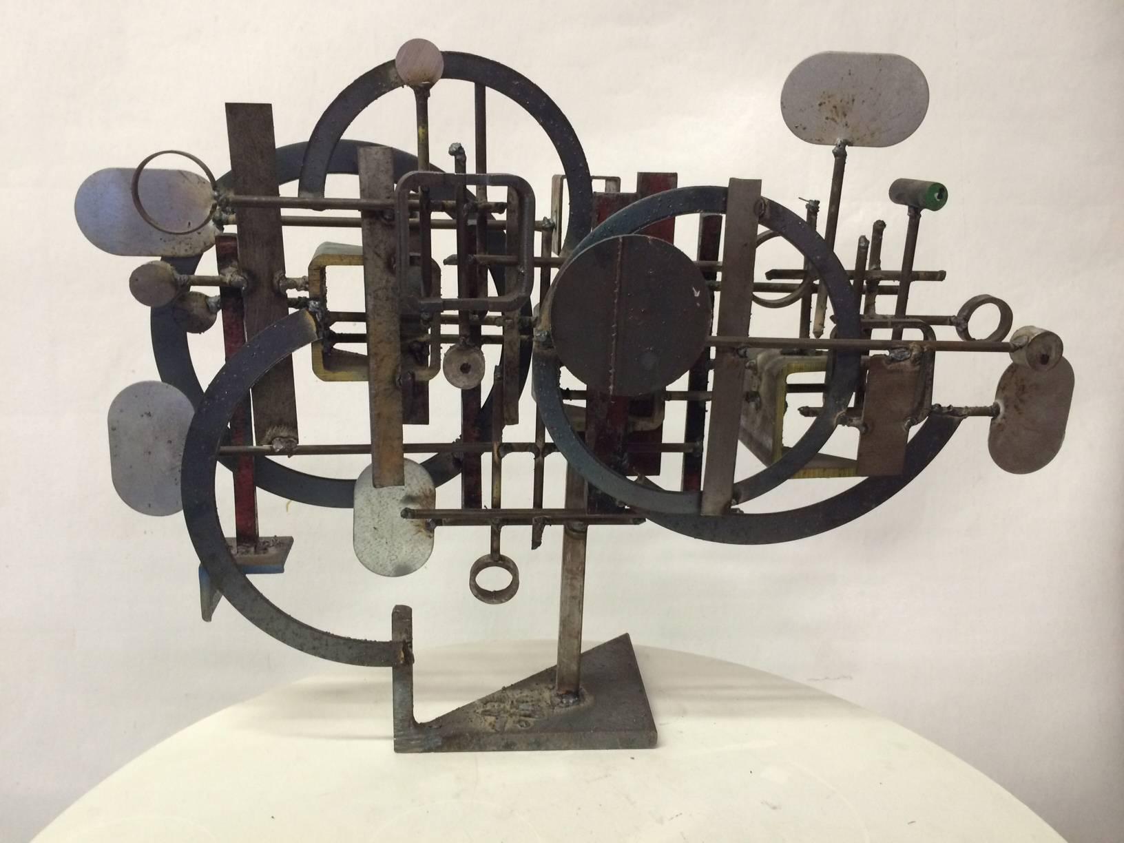 This table sculpture is the work of California artist Frank Cota. The piece's composition - an interplay of circular, square and rectangular forms - creates an eye-catching Brutalist form. The metal has great patina with some rust and faded paint.