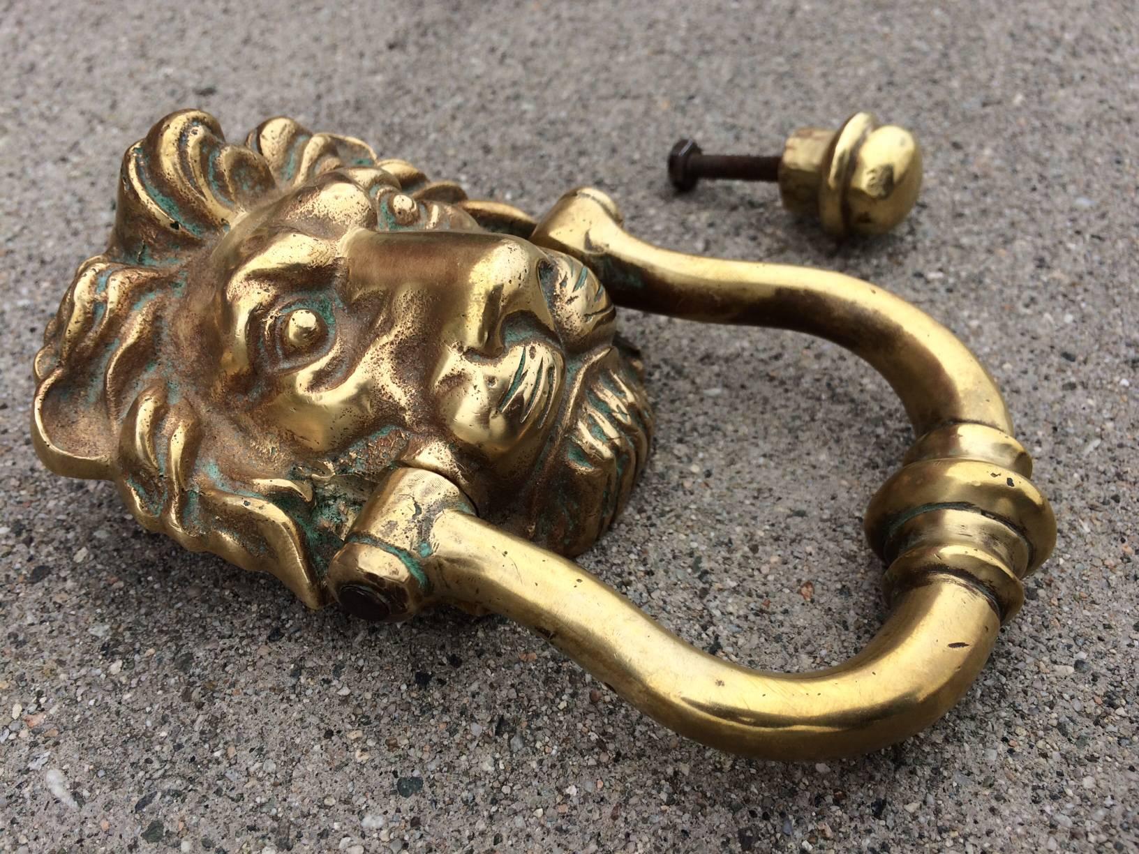 This door knocker in the image of a male lion is made of solid cast bronze. The piece has two parts- the main piece with the knocker and the other a round ball. Both mount to the door separately. Ball portion is a little over 1