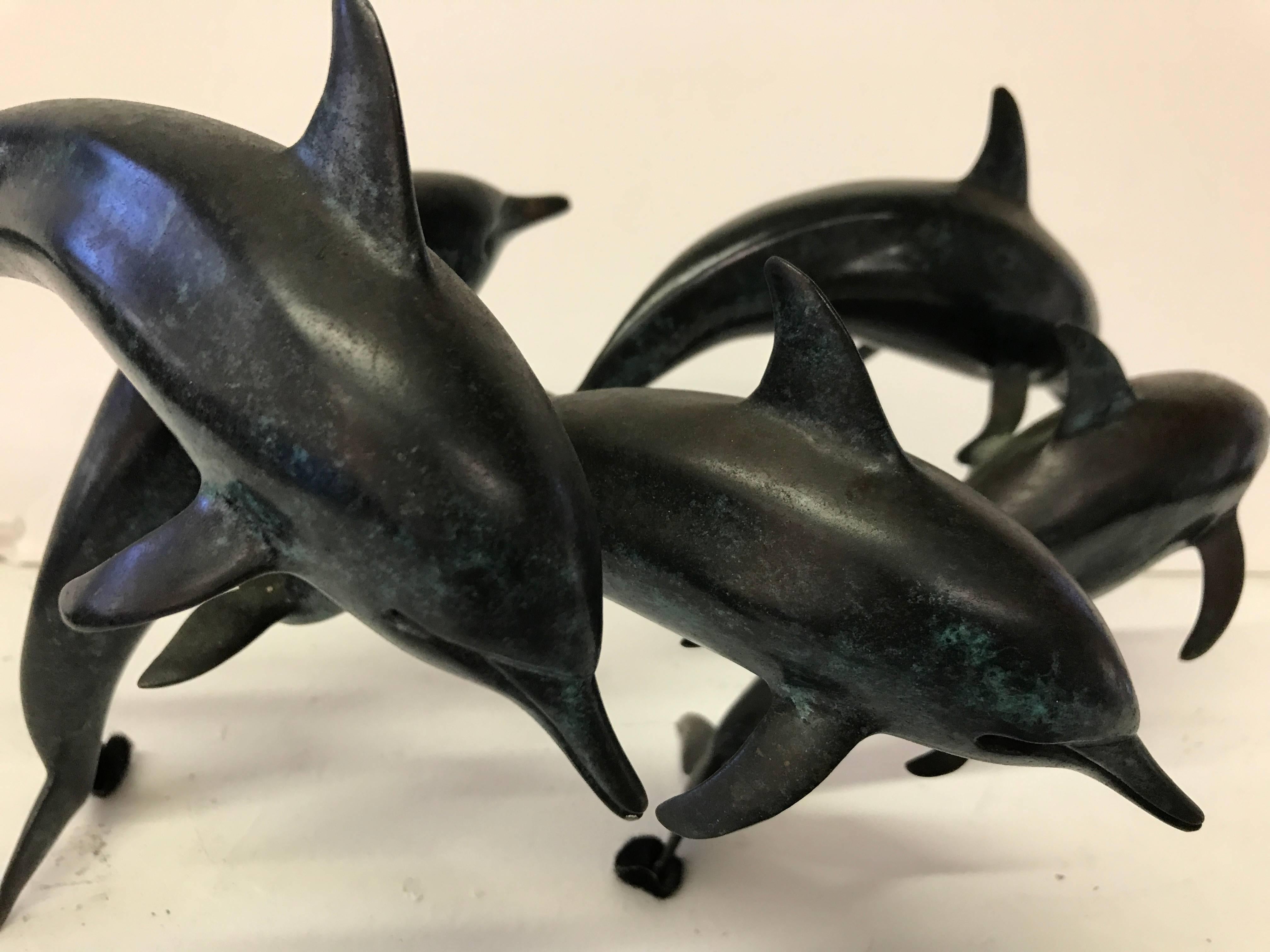 Bronze signed and dated 1988, limited edition 13/50, of dark blue patination and modelled jumping and diving dolphins.