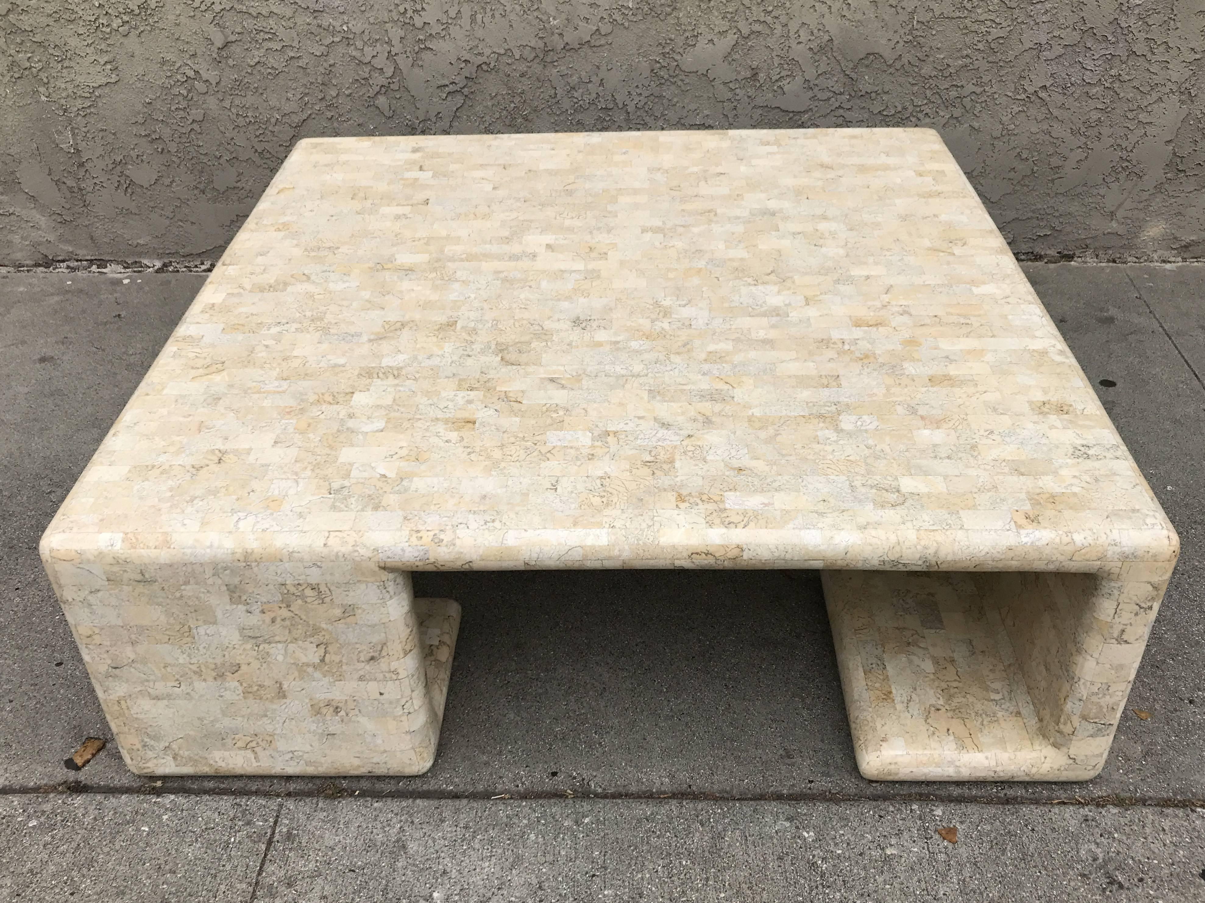 This coffee table by Maitland-Smith is made of tessellated fossil stone and its very unique legs bend under in alternating directions. The table is labelled "Designed and Handmade in Cebu, Philippines by Maitland-Smith, Ltd".