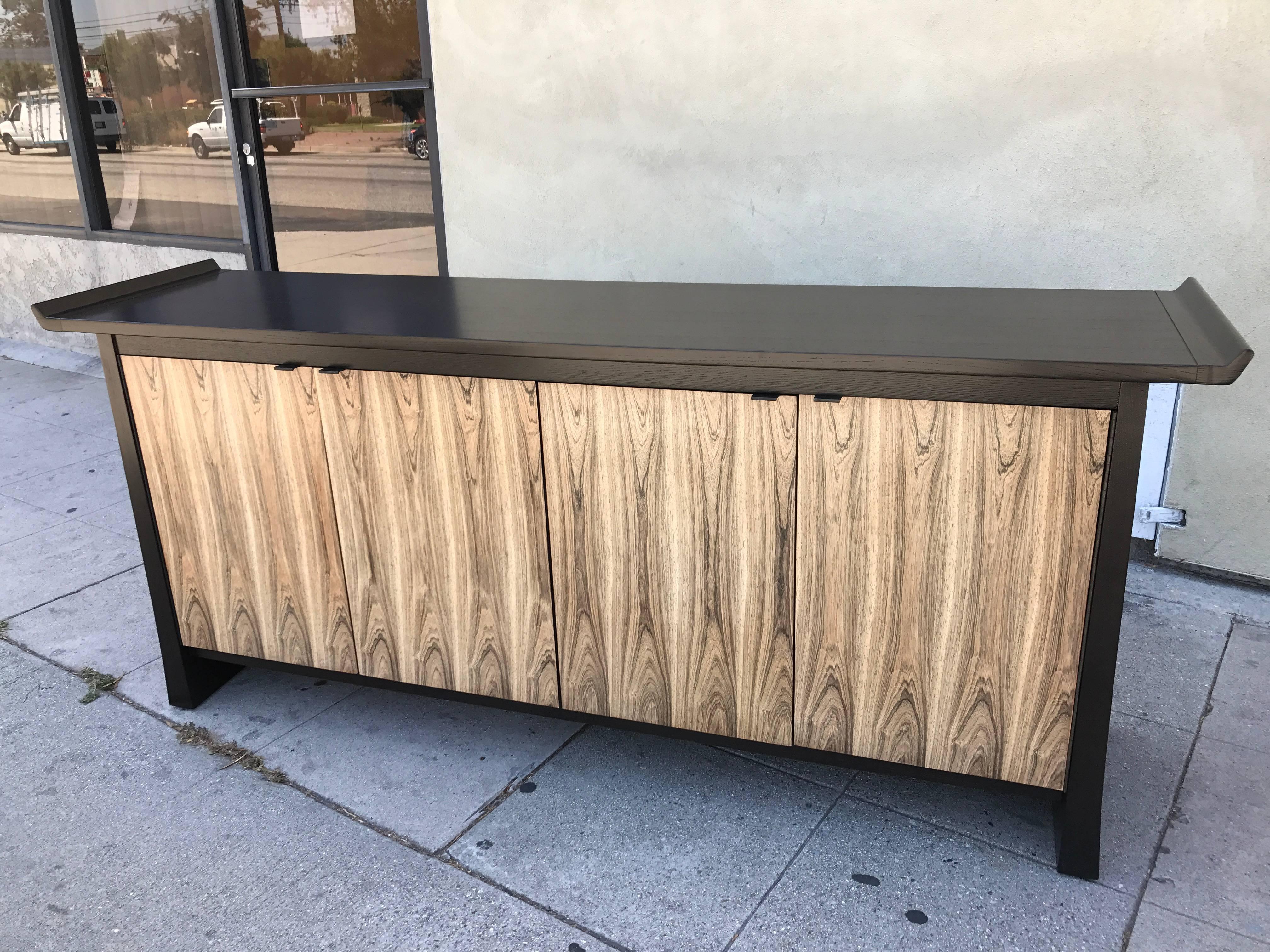 This sideboard is made of ebonized walnut for the body and bleached rosewood for the four doors which open on a shelf on the right and three drawers on the left. Made and stamped by Bernhardt Flair Division.