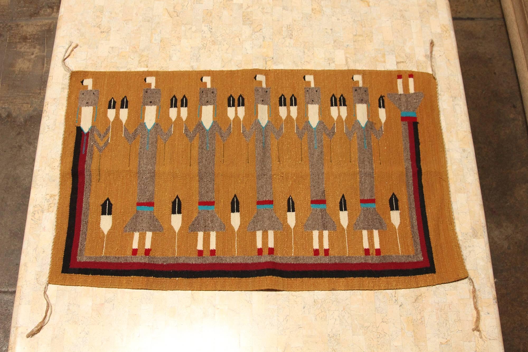 A pictorial weaving with a unique composition featuring three Yei (Yeibichai) figures holding one feather in each hand. According to Navajo belief, a Yei is a supernatural being or a holy one with healing powers. Yei can be male or female and are