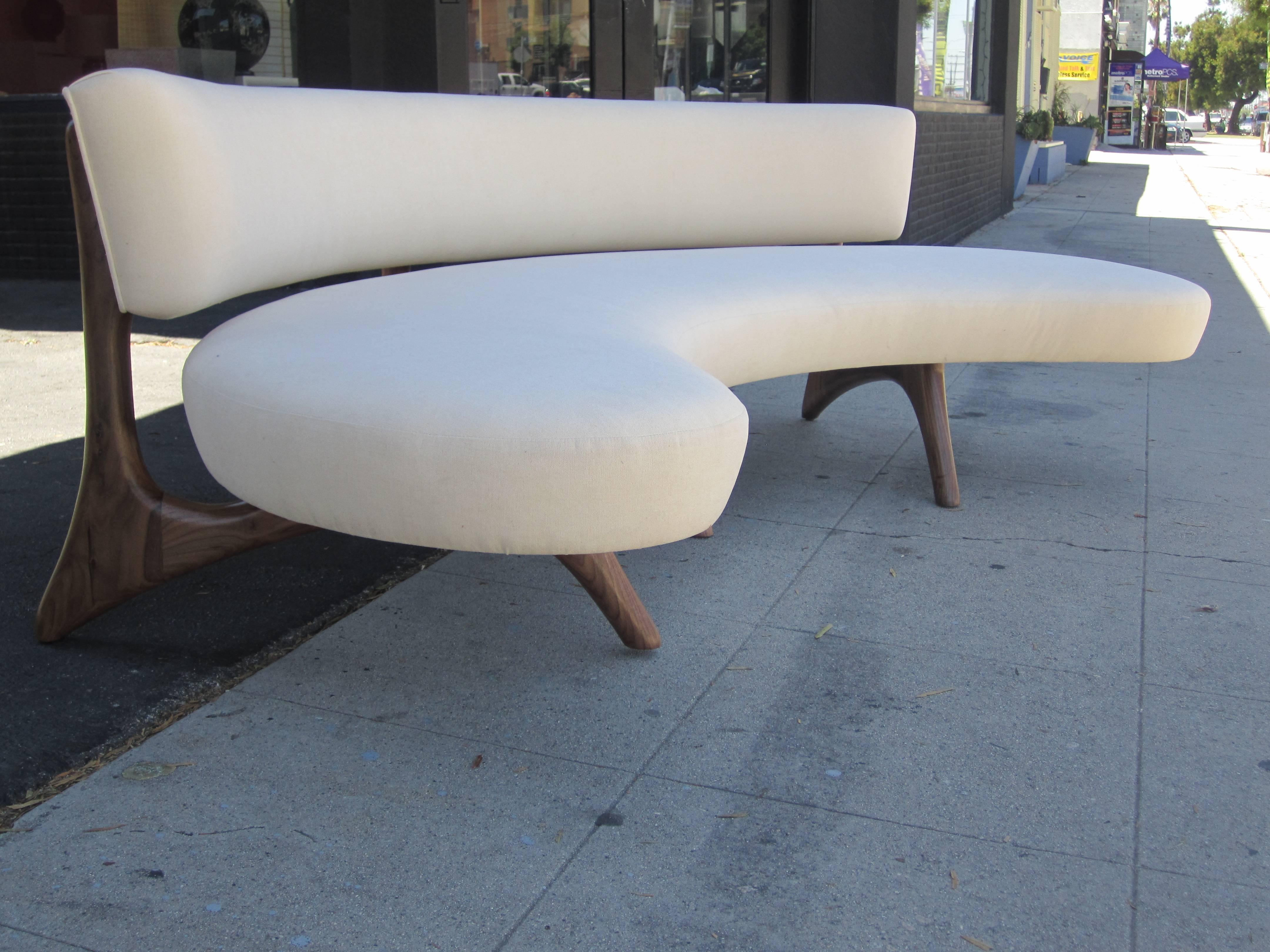 A biomorphic walnut sofa with curved backrest and a floating platform seat set on sculptural carved legs which blend seamlessly into the support for the back. Please contact us about the fabric options available.