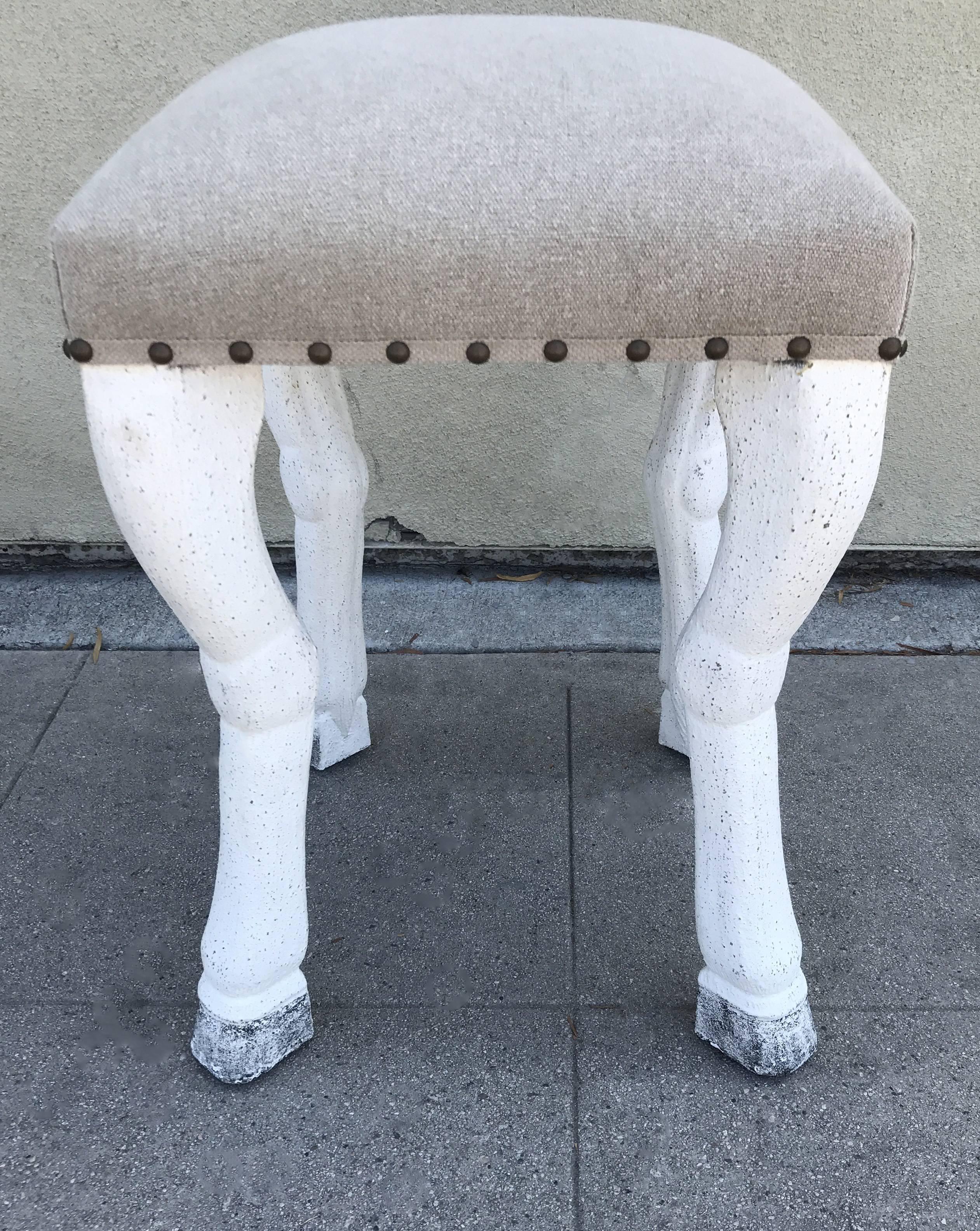 Stool upholstered in beige canvas has white washed, zoomorphic legs resembling animals hooves. Seat itself measures 16.0" x 16.0".