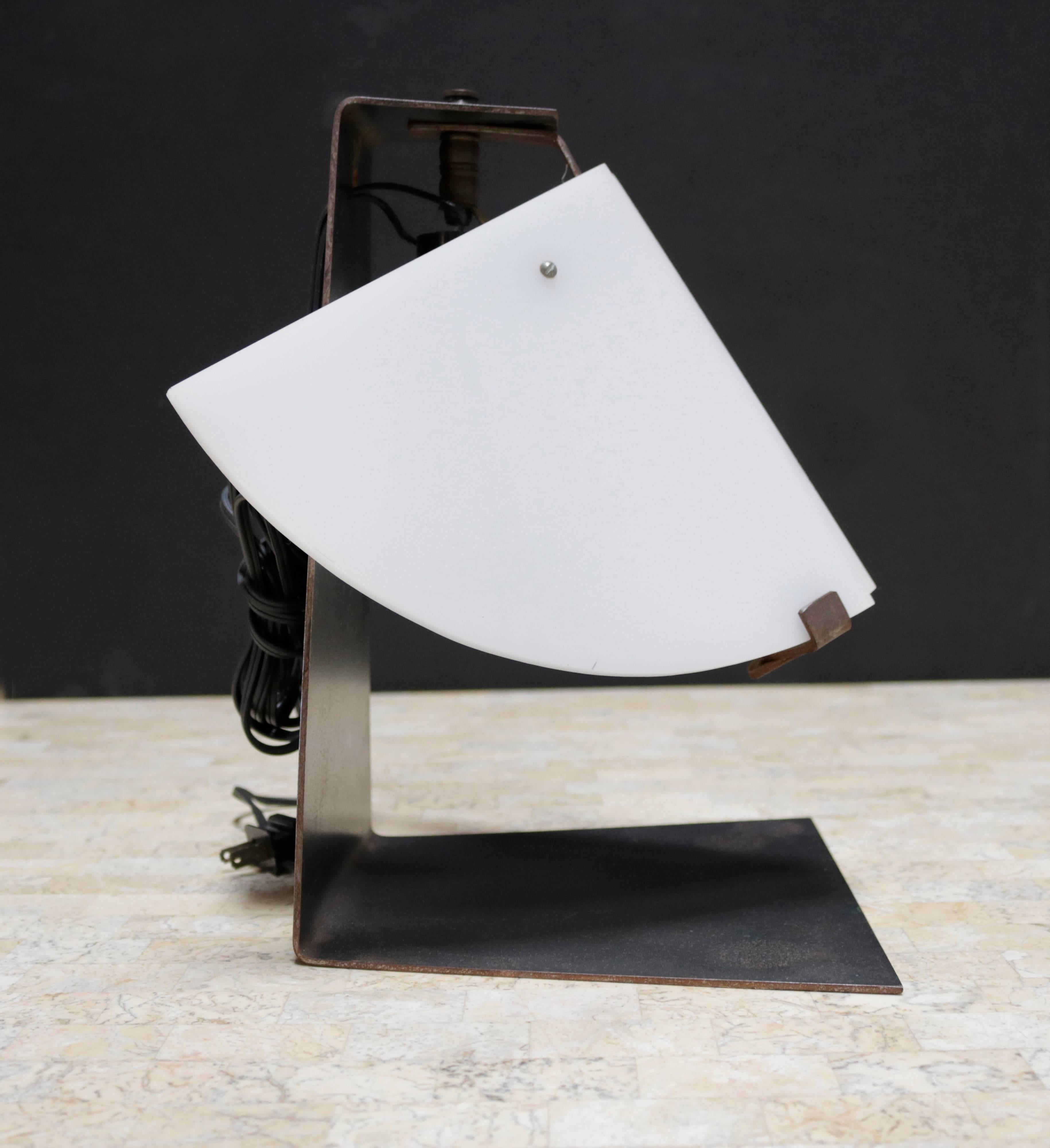 This cubist inspired piece was originally designed in 1922 by Pierre Chareau.

Made up of a base in forged blackened metal and darkened wrought iron with two panels of plexiglass in quarter-wedges, this adjustable lamp has probably been made by a