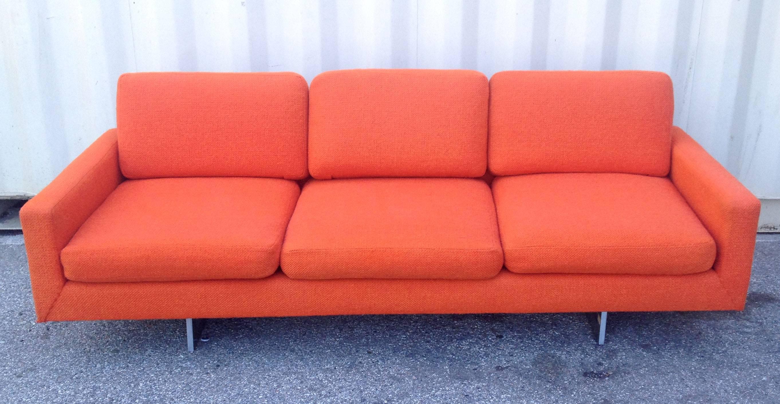 This Mid-Century Modern sofa features bright orange upholstery that is in very good original condition. The three-seat sofa sits upon two rectangular chrome bases set inside which gives it a floating look.
This design reminds the work of Milo