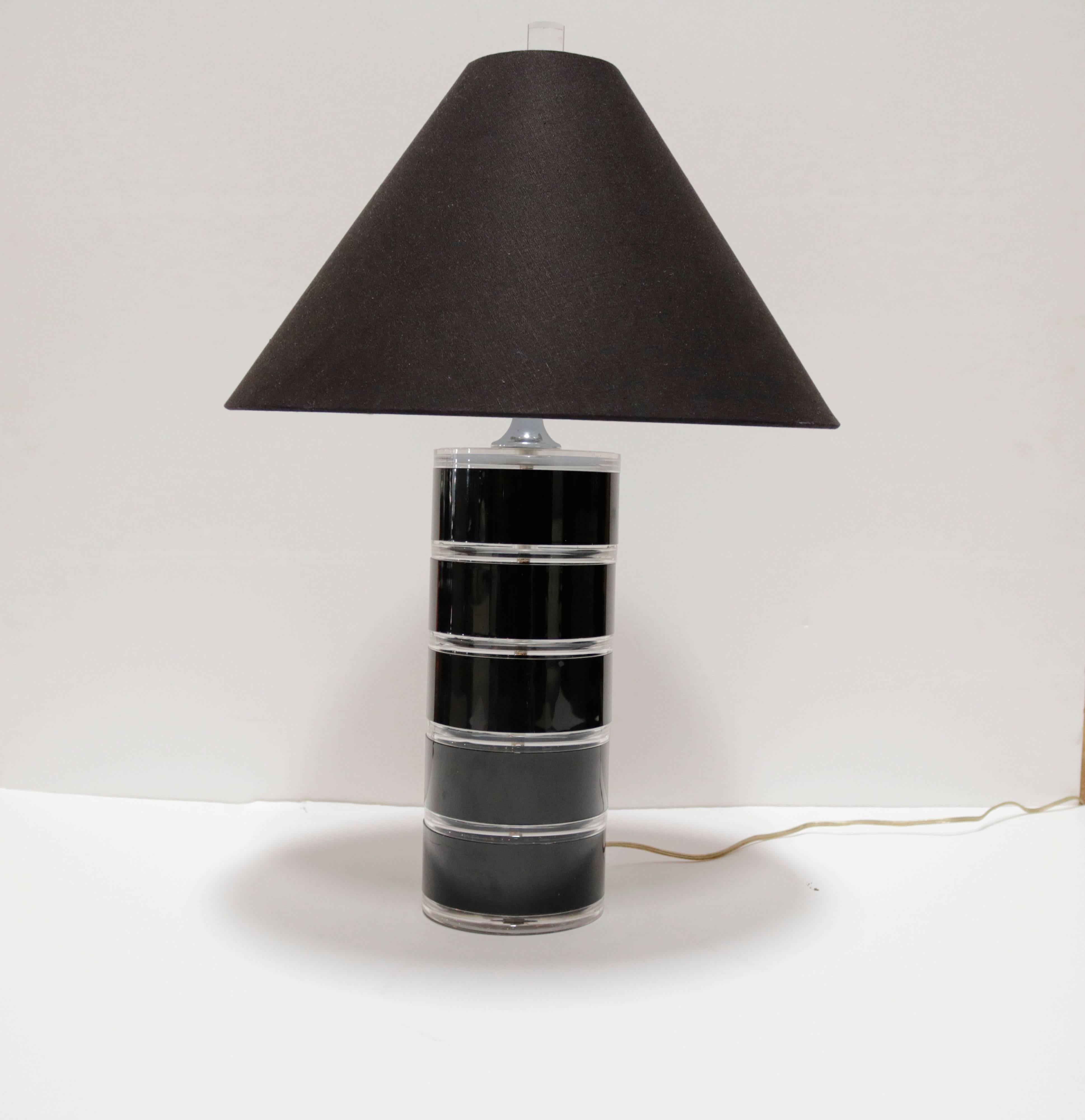 Cylinder shaped clear and black Lucite table lamp with new black paper shade. Lamp measures 25.0