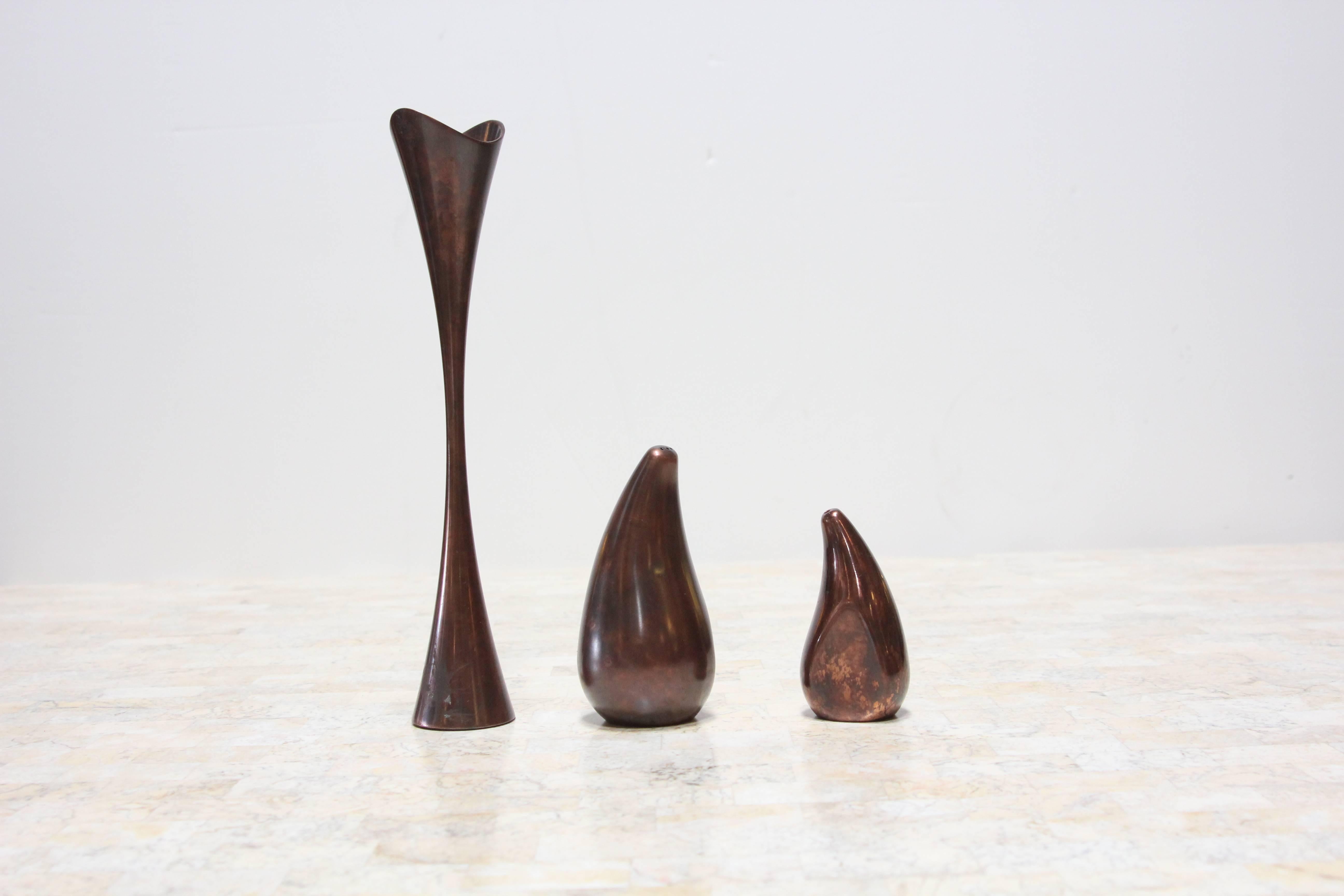 Set of three pieces in patinated copper by Nambe.
Salt and pepper shakers which each have one flat edge and fit perfectly together, and a matching candleholder. Inside of candle holder is cleverly designed so that it can hold either a votive or