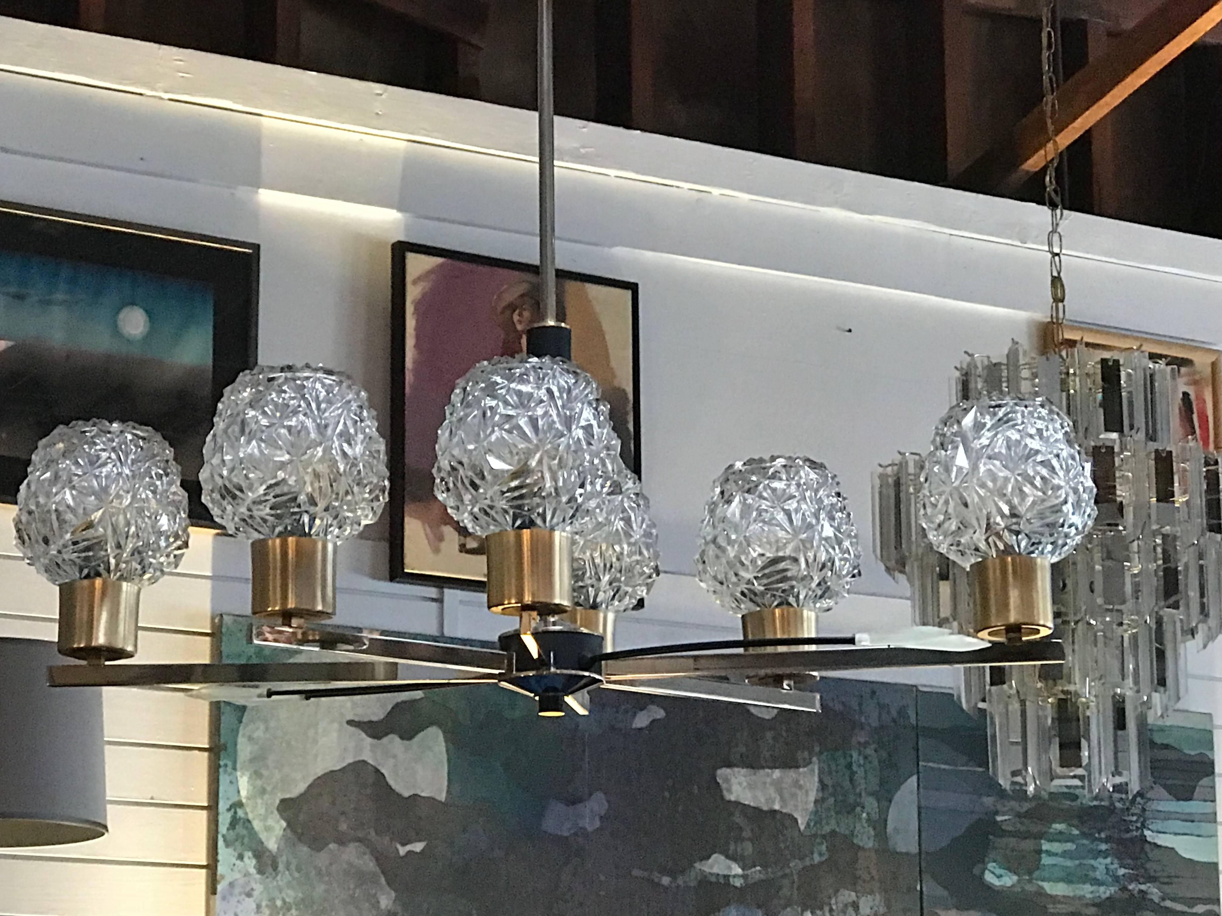 This chandelier features a brass frame with six molded glass globes.