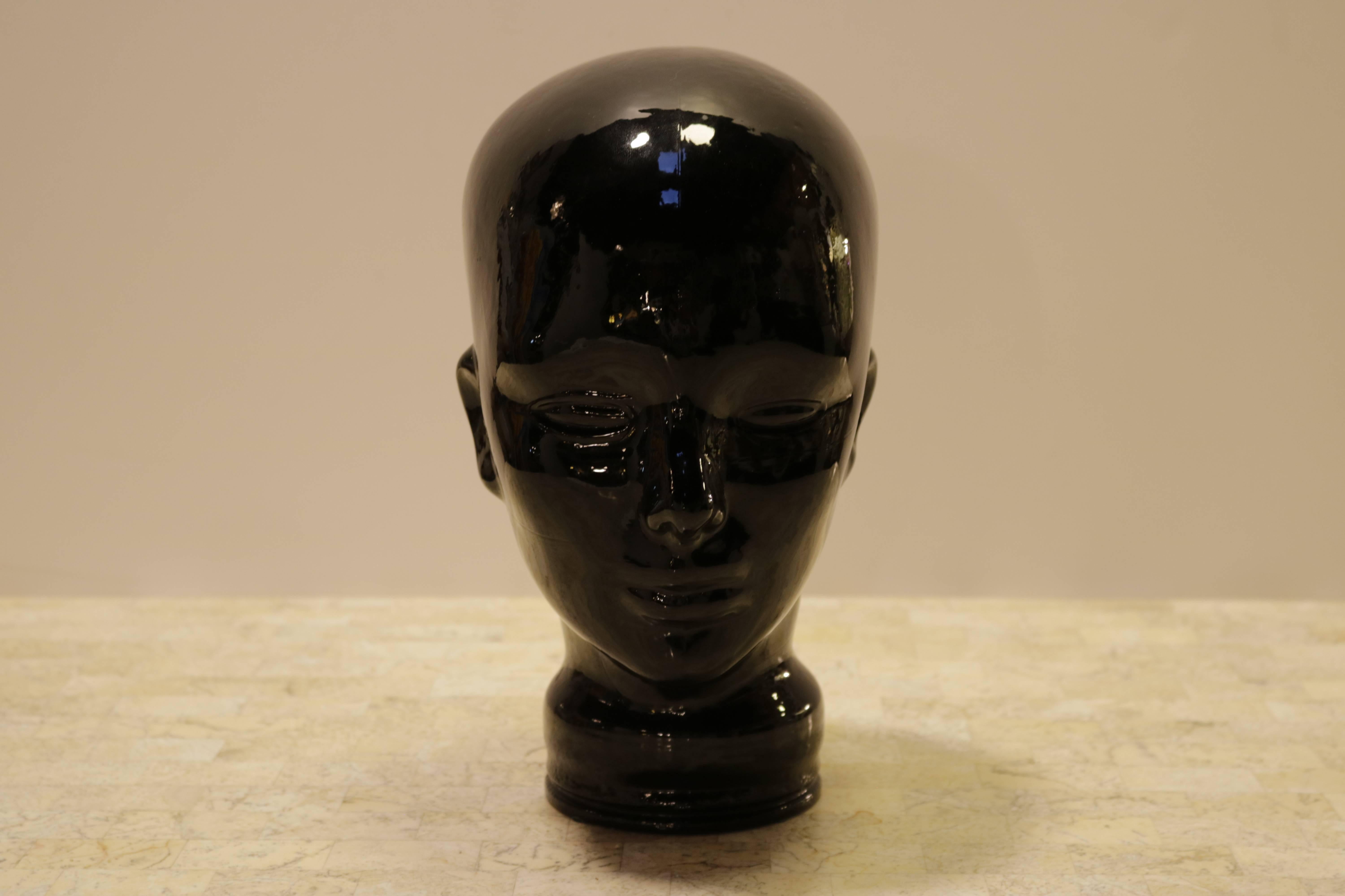 Sculptural black glass head. Hollow with an opening at bottom.