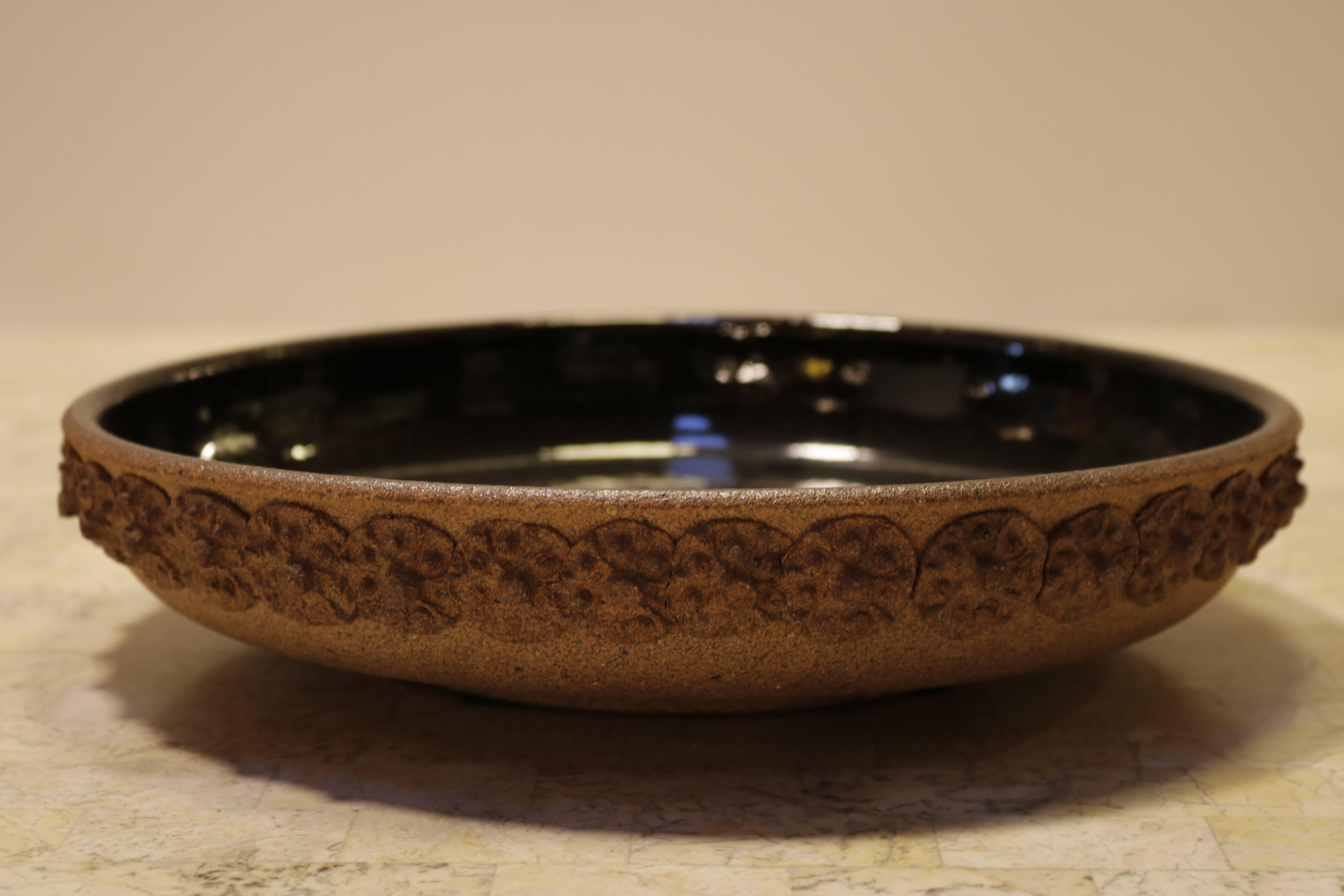 Terracotta decorative bowl is glazed espresso brown inside and a dimensional floral motif. Signed by probably a Californian artist but is illegible.