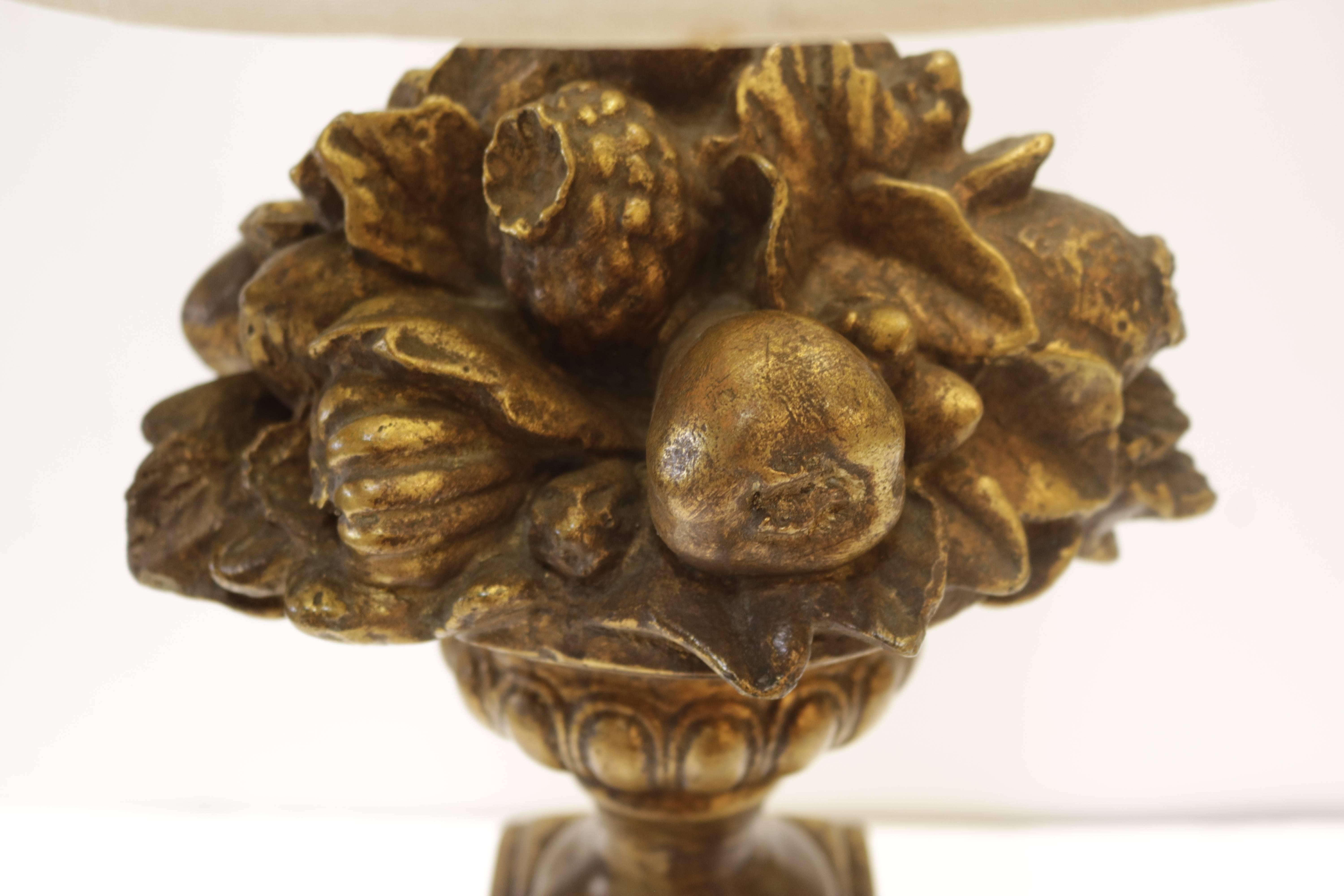 Slim original gilded wood table lamp has various fruits and flowers carved and retains its original off-white silk shade which is in excellent condition.

As pictured with shade, the lamp measures 9.0