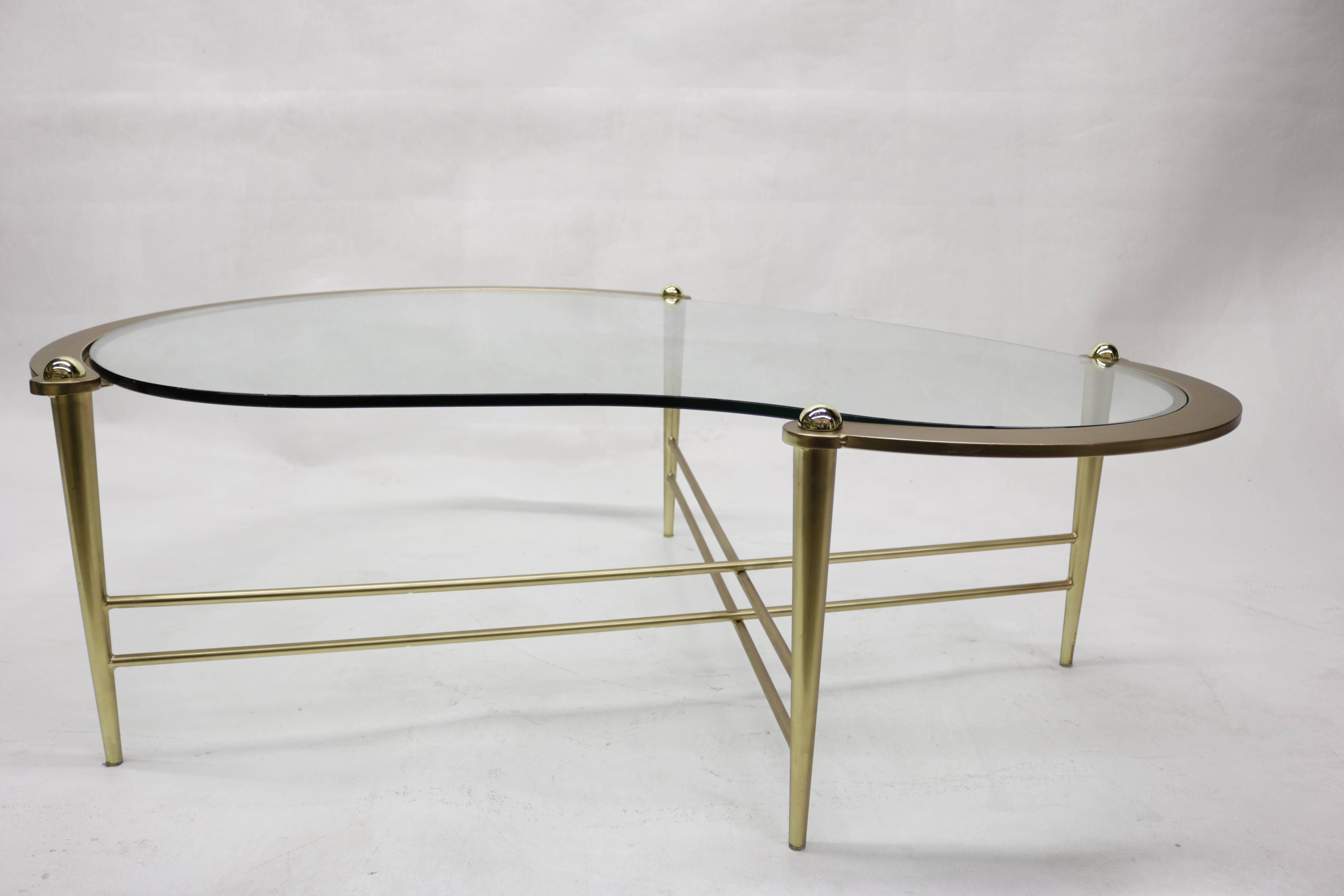 1960s coffee table has a kidney shaped glass top and delicate shaped gilded brass base.