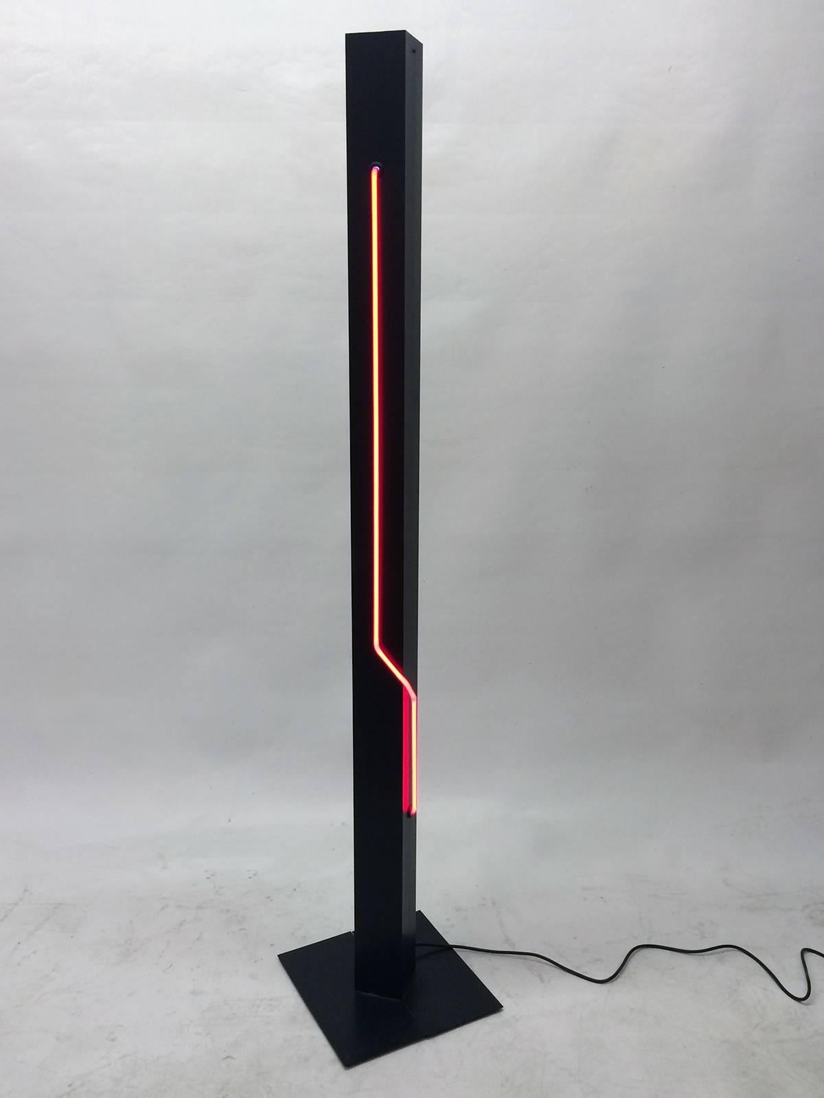 This black floor lamp has a red vertical neon bulb that wraps around a corner to cover two sides.  The neon is controlled by one switch and there is a second dimmer switch that controls the top halogen bulb.  Very cool addition to the right space. 