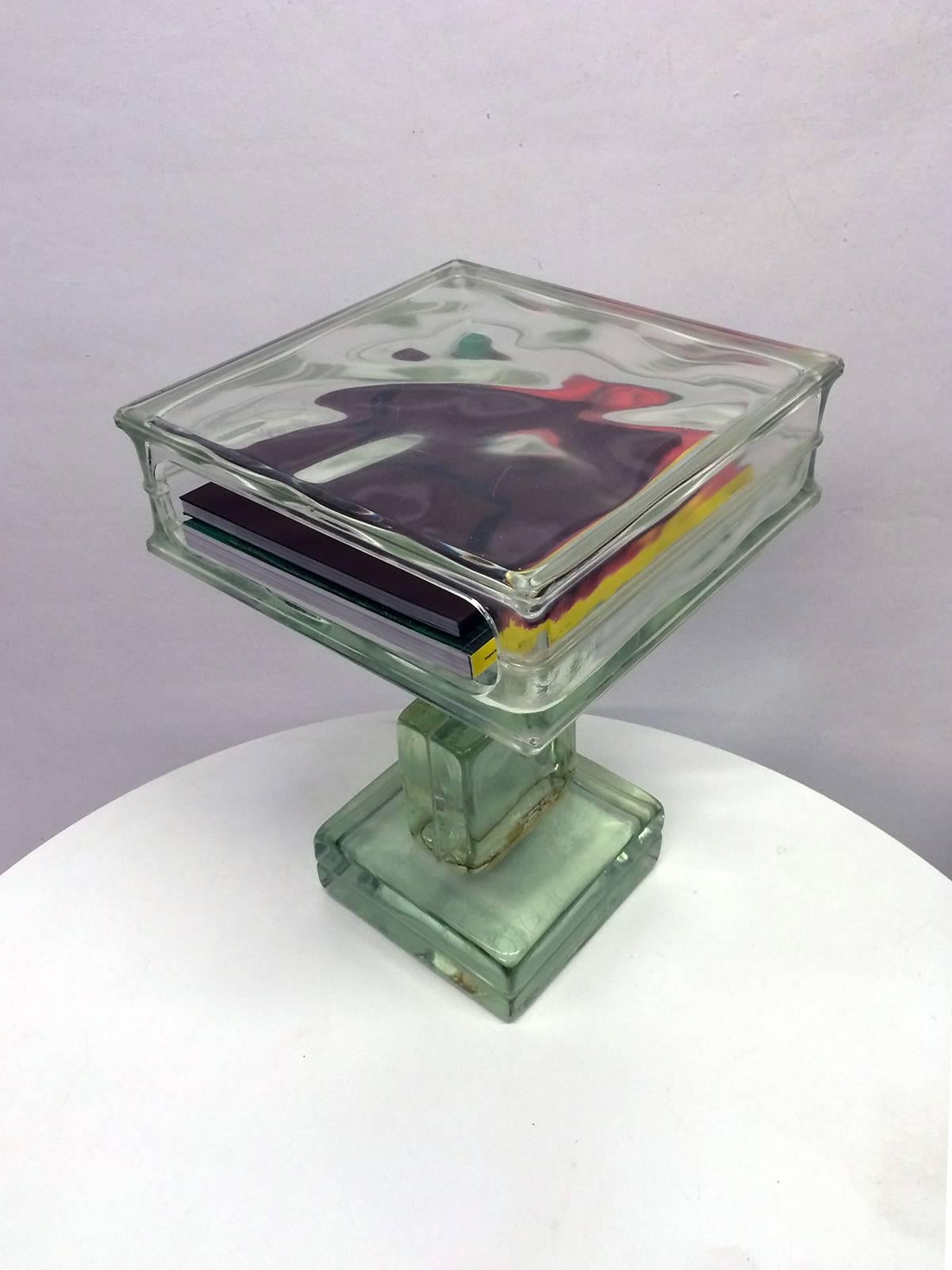 Side table constructed from four glass blocks. The cube that forms the table top has one open side allowing for the storage of magazines or books. This is a very unique piece.