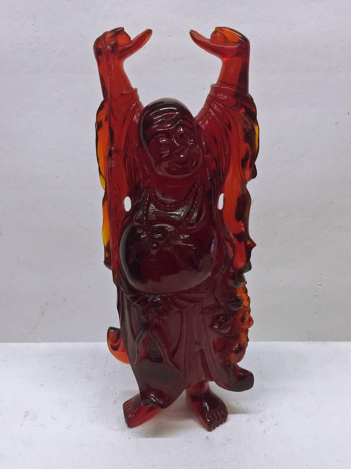 Cast resin sculpture of the Buddha.  Jolly, playful and light feeling in the transparent red resin of this very special Buddha.   
It sits on a lucite base  