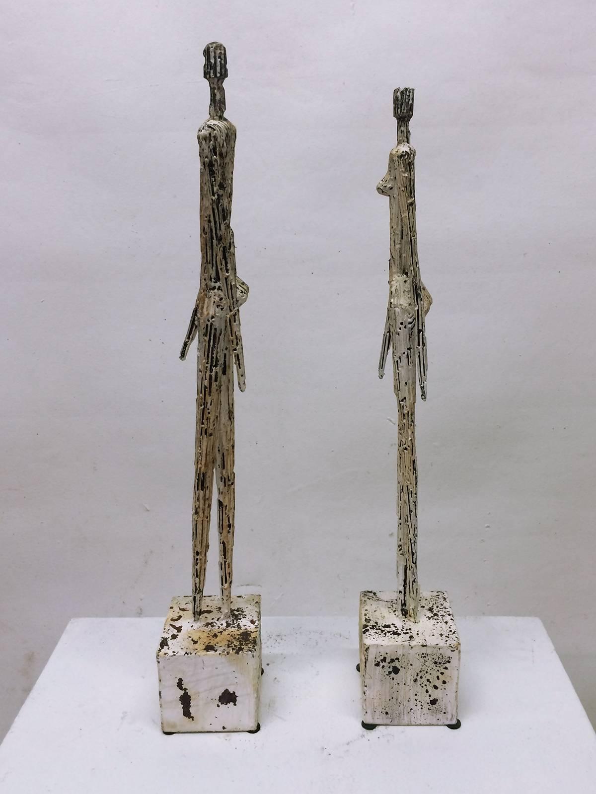 Two  metal figures, one male and one female,  in a style similar to that of Alberto Giacometti.  The figurative sculptures feature a distress look .