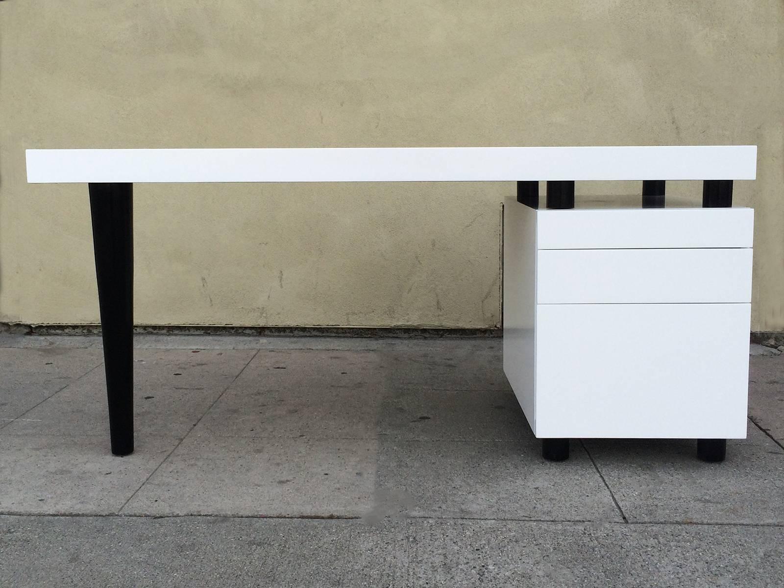 Architectural three-drawer desk in white and black lacquer.
This 