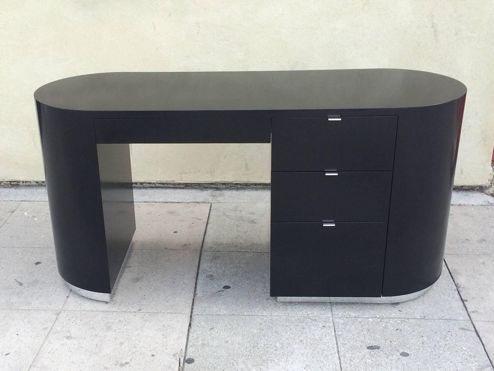 An architectural black lacquer desk with four drawers. This desk features round sides, three inches stainless steel base  and chrome pulls. 
This desk could have been design by Karl Springer or Pace.  It is part of a bedroom set including a long