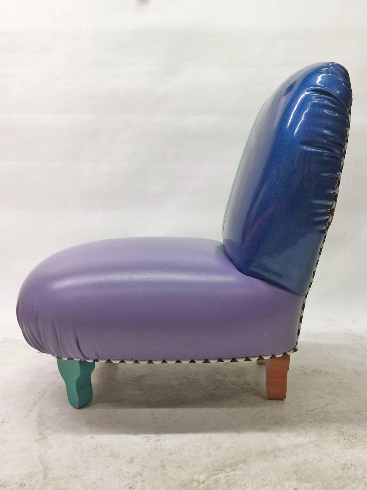 This playful Memphis inspired slipper chair by 1980s Los Angeles designer Harry Siege is finished in primary and secondary colored vinyl. Detailing is completed with black and white pyramid piping and legs in green, red, orange and yellow. The blue