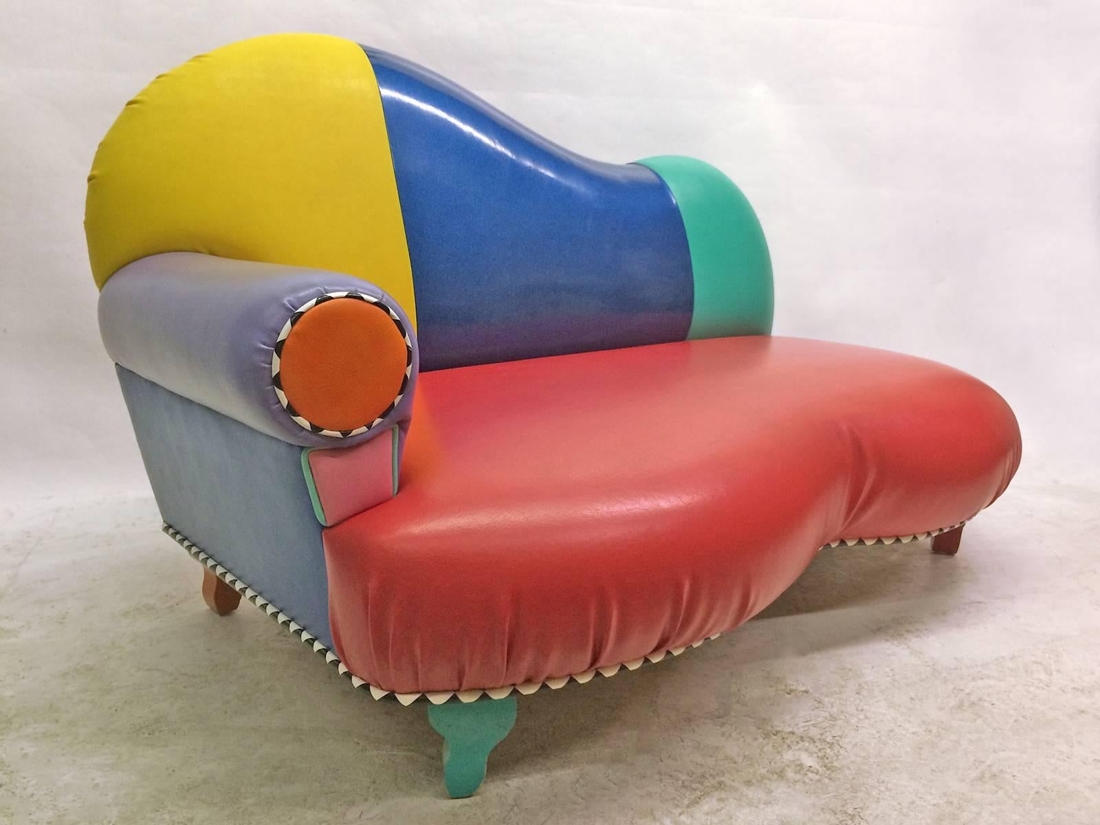 This playful Memphis inspired sofa, loveseat or chaise by 1980s Los Angeles designer Harry Siegel is finished in primary and secondary colored vinyl. Detailing is completed with black and white pyramid piping and legs in green, red, orange and