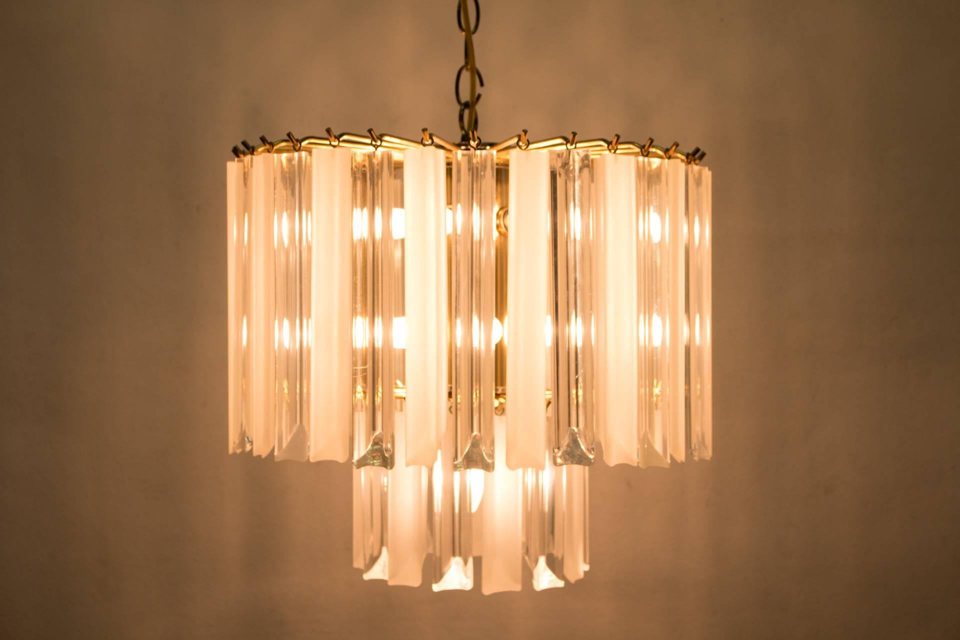 This Lucite chandelier has two levels of alternating opaque and transparent dangles of long, rectangular Lucite prisms. The outermost plane's dangles are ten inches long and the inner plane houses six-inch dangles. The minimal frame and canopy are