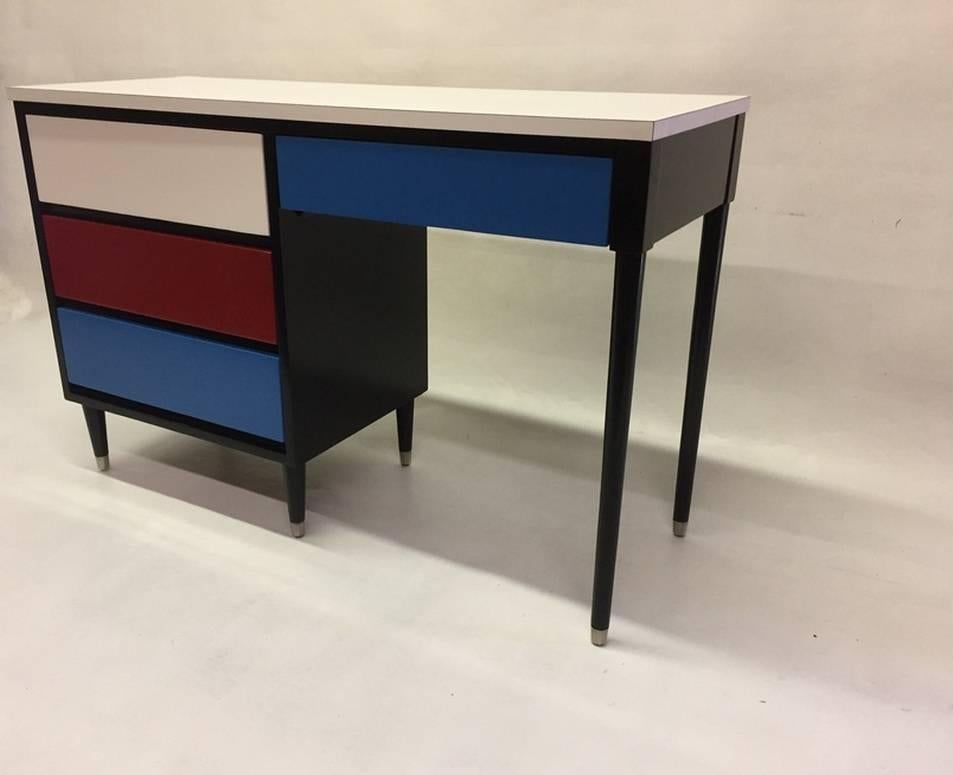 This 1950s desk features blue, red and white lacquered interchangeable drawers in a black frame.