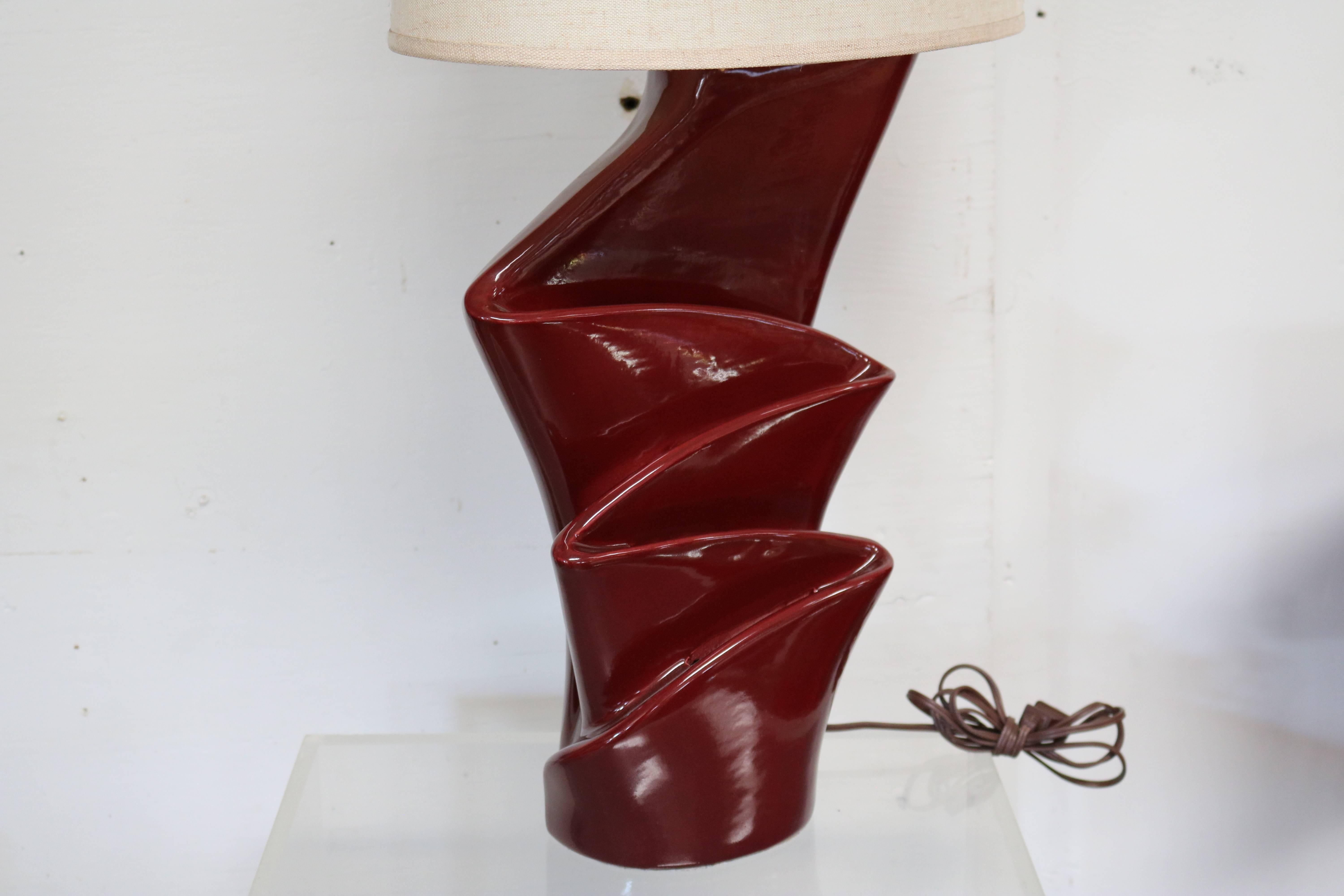 Pair of table lamps featuring a draped, curtain-like base rendered in ceramic coated with deep red glaze. The lamp bases illuminate separately from the top bulbs. Wired and in working condition. Light settings allow for bases only, top bulbs only,