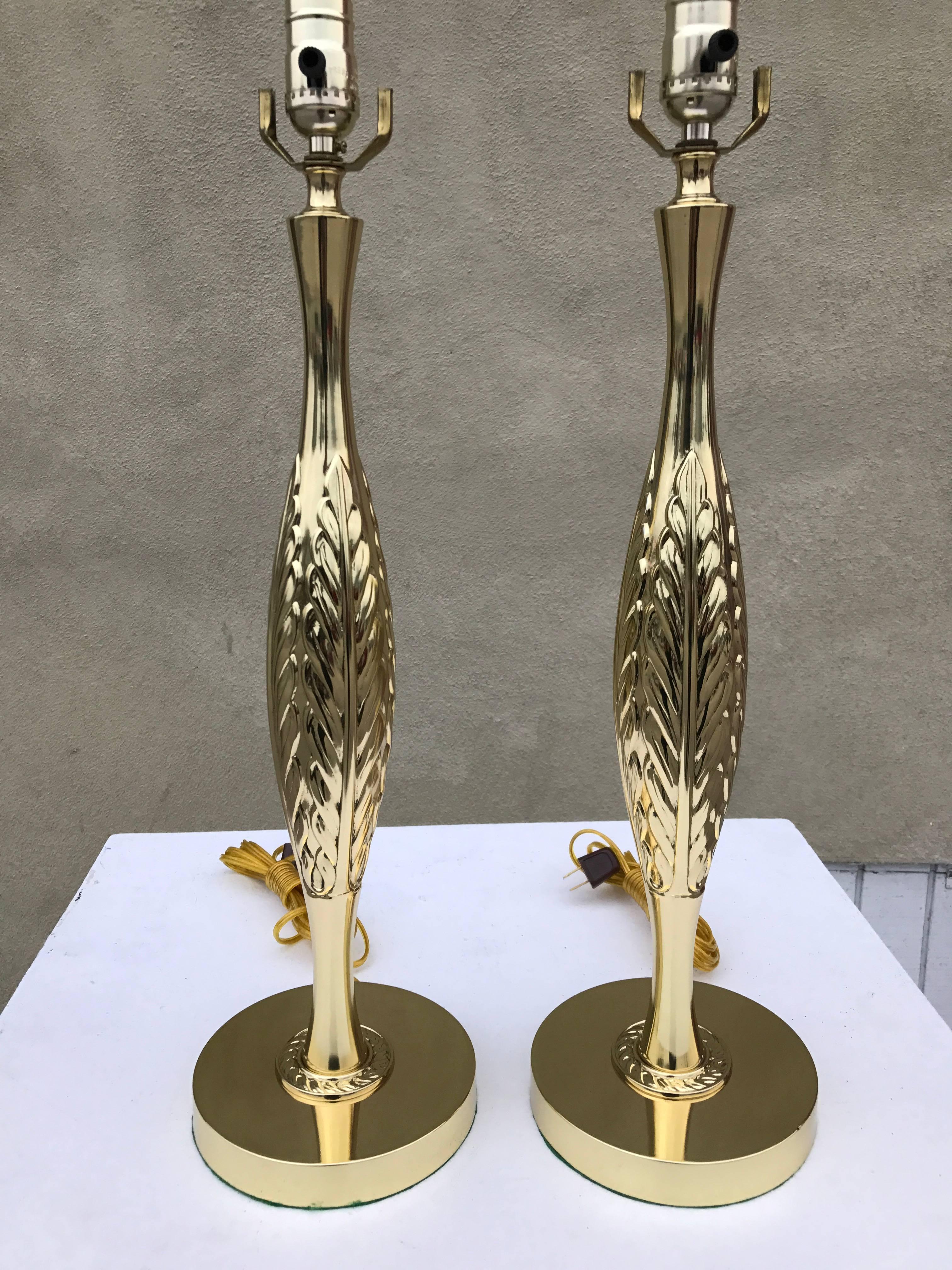 Pair of brass 1960s table lamps with leaf detail in relief. 
This elegant pair of Hollywood Regency Laurel table lamps features a brass body with acanthus leaf motif in relief. 
 The lamps are in perfect condition and have been newly rewired. Base